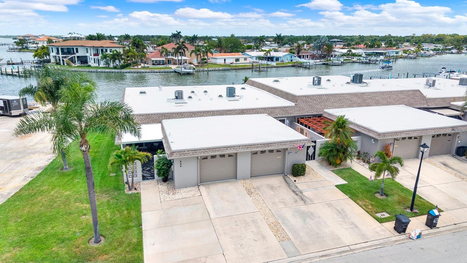 RARE opportunity to own a truly exceptional END UNIT WATERFRONT VILLA in the highly sought-after waterfront 55+ community of Boca Ciega Point! This one-of-a-kind STUNNING residence has been thoughtfully updated from top to bottom with custom-designed, high-quality finishes and offers a perfect blend of luxury, comfort, and waterfront living. A welcoming tropical courtyard sets the tone for this beautiful home, featuring a tranquil wall fountain, lush tropical landscaping, and an artist-painted cement floor. Inside, the light-filled open floor plan showcases a dreamy remodeled kitchen, with a large island, breakfast bar, abundant cabinetry, marble countertops, coordinating backsplash, and new stainless-steel appliances. The sliding glass door with built-in blinds seamlessly connects the kitchen to the outdoor patio area. The spacious dining and living areas are enhanced by a solar tube that fills the home with natural light, opening to an expansive Florida room with breathtaking, unobstructed Intracoastal Waterway views! This incredible space is designed for relaxation and entertaining, where you can enjoy spectacular sunsets, dolphin visits, and the beauty of waterfront living. Custom wall-to-wall blackout blinds provide privacy when desired. The primary suite offers direct access to the Family room, a WALK-IN CLOSET, and a beautifully updated ensuite bath. The generous 2ND bedroom provides convenient access to the private courtyard. Additional features include INTERIOR LAUNDRY, a freshly painted garage with impact door, and a driveway with parking for 2 vehicles.This home is loaded with upgrades (!) including a new water heater, roof (2018), HVAC (2017), added insulation, wood-look porcelain tile flooring, HURRICANE-IMPACT WINDOWS, solar-powered security cameras, attic fan, and more! Located near the end of the peninsula, this villa offers some of the most desirable views in the community, a PRIVATE DOCK WITH A 10,000 LB BOAT LIFT and an abundance of green space—perfect for pets and enjoying the outdoors! Boca Ciega Point is a PET-FRIENDLY 55+ community offering an impressive array of amenities including 2 clubhouses, heated pool, pickleball, tennis, bocce ball, shuffleboard, fitness center, and an active social and boating club. Ideally located just minutes to the beautiful Gulf beaches of Madeira Beach, shopping, dining, and entertainment at Seminole City Center. Schedule your private showing today and experience the best of waterfront villa living! Don’t miss this one!