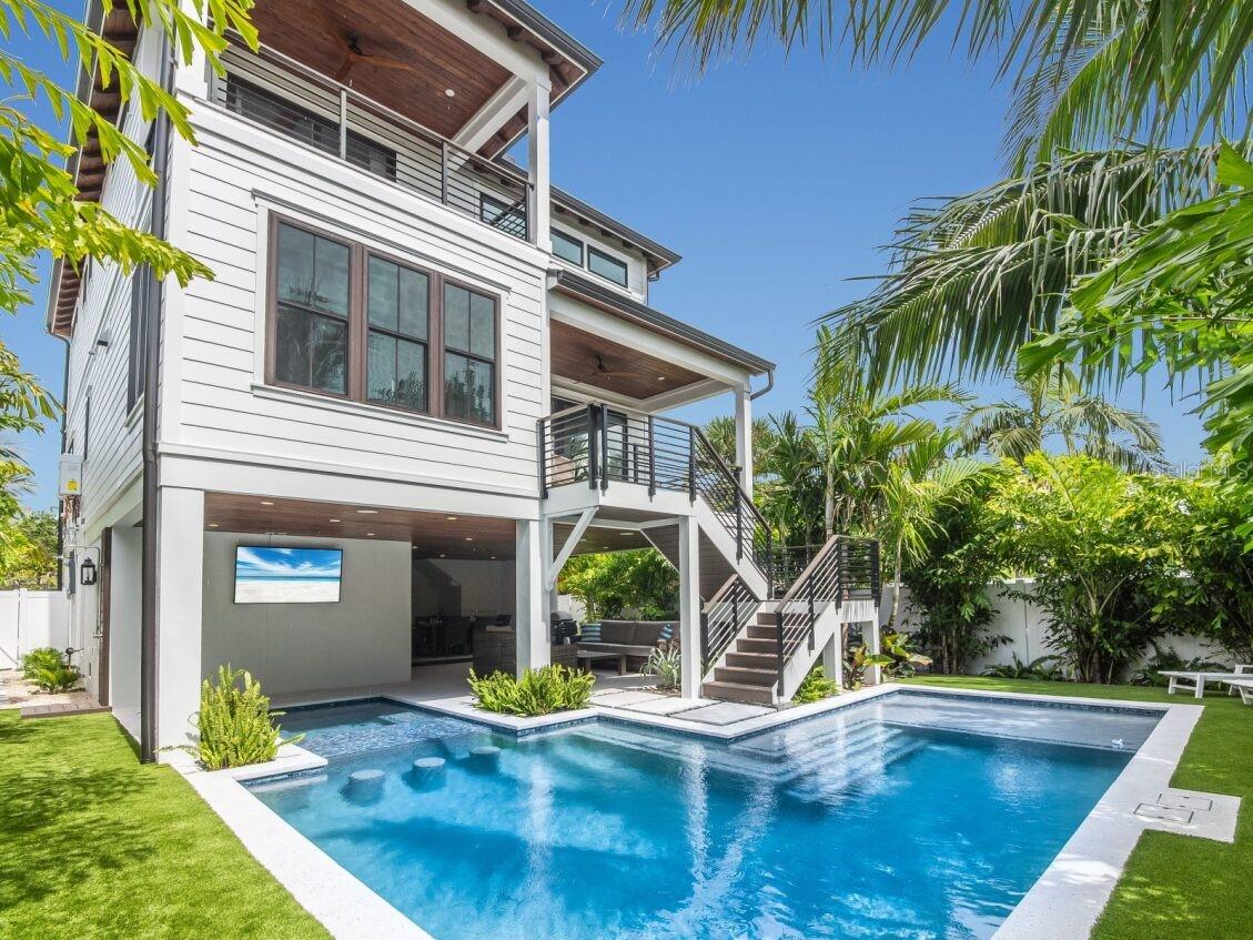 Big Price Reduction! Welcome to Luxe Island Escape, an exceptional new elevated 4-bedroom, 4.5-bath coastal retreat in the heart of Anna Maria Island. Offered fully turnkey furnished, this home is ready for you to immediately embrace the Anna Maria lifestyle, whether as a luxurious second home or a high-performing vacation rental.

Designed with coastal sophistication and thoughtful attention to detail, the residence is surrounded by lush tropical landscaping and features a private heated pool and spa, plus an expansive rooftop deck offering sweeping views of the Gulf of Mexico and Tampa Bay—perfect for sunset gatherings or relaxing afternoons with family and friends.

Inside, the bright, open-concept floor plan boasts soaring ceilings, custom contemporary finishes, and a designer kitchen with sleek stainless-steel appliances, a striking island, and abundant space for entertaining. The main living area flows seamlessly onto a covered deck, inviting in the sea breeze and natural light. Two guest suites on the main level each include private baths, offering comfort and privacy for visiting family or vacation guests.

Upstairs, the serene primary suite opens to a private deck—ideal for peaceful mornings or quiet evenings—and includes a versatile sitting area or office space. The rooftop deck provides panoramic island views, perfect for taking in the vibrant coastal scenery and breathtaking sunsets.

Ideally located just a 2-minute walk to Tampa Bay and only 5 minutes from the pristine sands of Bean Point, this home blends tranquility, island beauty, and luxury living. Currently operating as a busy vacation rental, Luxe Island Escape represents a rare opportunity for full-time ownership, seasonal escape, or turnkey rental income.

Schedule your private showing today and start enjoying the Anna Maria Island lifestyle immediately.