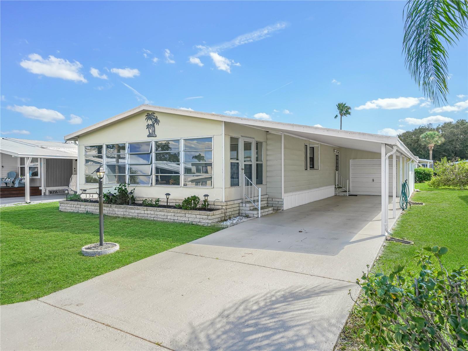 One or more photo(s) has been virtually staged. 2-Bedroom, 2-Bathroom Mobile Home in a 55+ Community of ORANGE MANOR WEST-NO LOT RENT!-This spacious 1,352 sq. ft. double wide mobile home located in a 55+ community that offers a wealth of amenities for an active lifestyle. BRAND NEW A/C! The living room features sliding glass doors that open to a front enclosed Florida room, perfect for enjoying the view of your front yard. The kitchen comes fully equipped with all appliances and a separate dining room for your meals. The main bedroom boasts an en-suite bathroom and a walk-in closet. The second bedroom is adjacent to a recently updated bathroom. Inside laundry room with additional storage, washer, and dryer included. A long carport that can accommodate two cars, with a garage door leading to extra storage space. Roof: Installed in 2017. Community Amenities: Pool, Clubhouse with billiards and library,Putt-putt golf, Bocce ball and horseshoe fields, Shuffleboard and Basketball court. Please note, this park does not allow pets. Don’t miss out on this wonderful opportunity! Call now for more details.