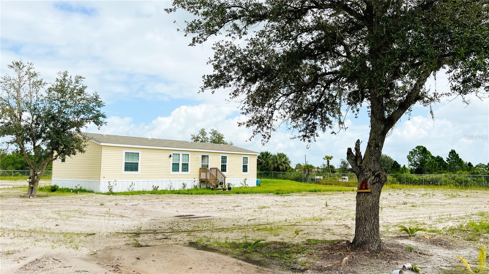 Welcome to your private sanctuary on 2.5 acres! Seller Motivated!
2023 manufactured home -  vacant- 3 bedrooms/2 baths. Photos were taken prior to removing furnishings. Unfurnished now.
New appliances (washer/dryer do not convey). Owner added cabin/shed (12x24) can be used for storage or bedroom (not currently connected to utilities). See MLS listing attachment for cabin layout. Owner added the following enhancements; septic tank, additional tank and well, pond, 6' galvanized chain link fence, leveling of land, woods clearing, road inside gate, bridge outside gate, cabin/shed and anchor for shed. Enjoy the owner planted fruit trees, pomegranate--mango, apple, avocado, oranges, grapefruit, fig, soursop and see beauty and peaches. Click on TOUR button to see beauty and potential of this unique property. Come visit soon!