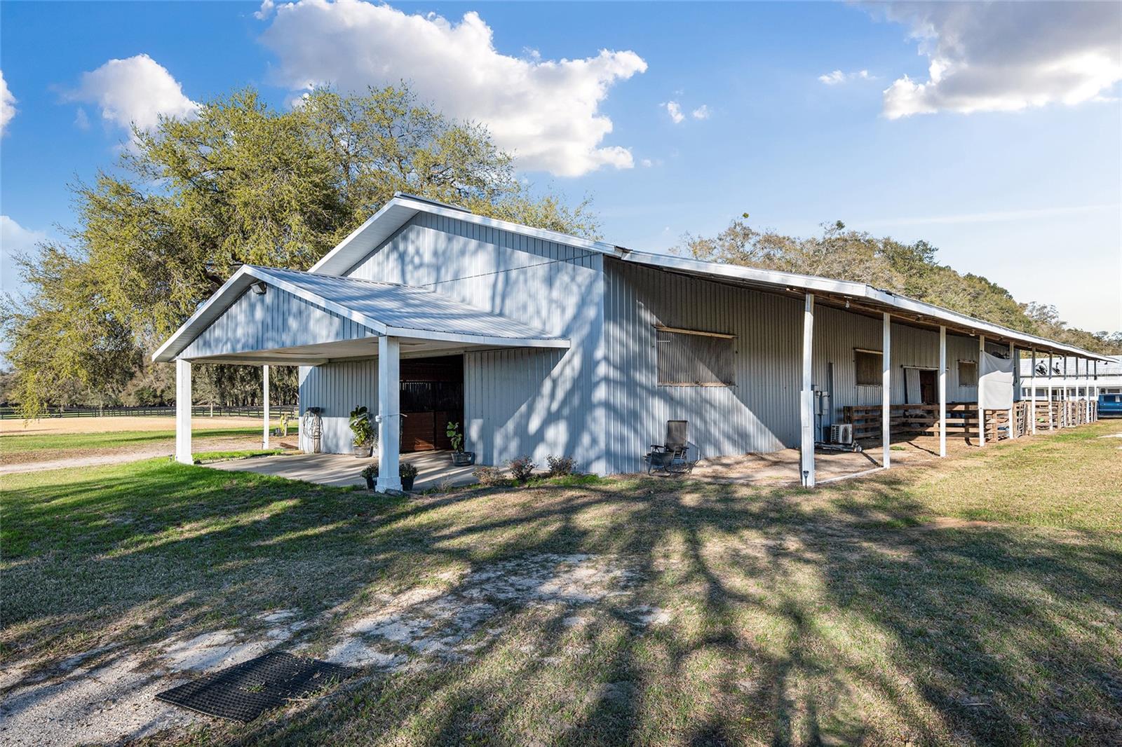 ADJACENT TO OCALA!!  Just minutes to the FLORIDA HORSE PARK AND THE WORLD EQUESTRIAN CENTER!!  This property is ready for you to make this your new dream farm!! This beautiful 12.97 serene acres is adorned with picturesque, mature granddaddy oaks and designed to accommodate any riding discipline!  IMPROVEMENTS TO THE PROPERTY INCLUDE NEW ASPHALT MILLING DRIVEWAY FROM ENTRANCE TO THE BARN, NEW CROSS FENCING AND NEW FENCE REPAIRS/REPLACEMENT. In addition to the improvements, the property features a beautiful 13-stall center-aisle barn, along with 7 covered shed-row catch stalls, AUTOMATIC WATERERS, RUN IN SHELTER & WASH RACK.  All stalls are 12×12 or larger and equipped with fans for year-round comfort.
The barn is thoughtfully appointed with a centrally located feed room, tack room, full bathroom, and laundry area, all individually air-conditioned, plus additional storage throughout. An impressive 80’ × 220’ riding arena with a clay base and sand/clay footing provides excellent rideability.
A Massive hay and shavings storage area offers ample space for feed and farm equipment. Additional features include a 50-amp RV hookup perfectly positioned beneath a majestic oak tree, as well as an additional hookup suitable for a smaller camper or living-quarters horse trailer under the barn overhang.
One of the property’s most desirable features—especially during the warmer months—is the lighted field. This versatile space is ideal for a jump course, polo field, dressage ring, practice arena, or any use that suits your needs. The entrance is enhanced by a new solar-powered gate, and as you drive down the lane, the expansive lighted field welcomes you on the right—an impressive and functional first impression.
Conveniently located with easy access to I-75, just minutes from the Florida Horse Park, and a short drive to WEC, this property offers the perfect blend of peaceful country living and accessibility. Close to hospitals, dining, shopping, and The Villages, it is both easy to reach and ideally situated.
This is truly a must-see property to fully appreciate its beauty, functionality, and setting.