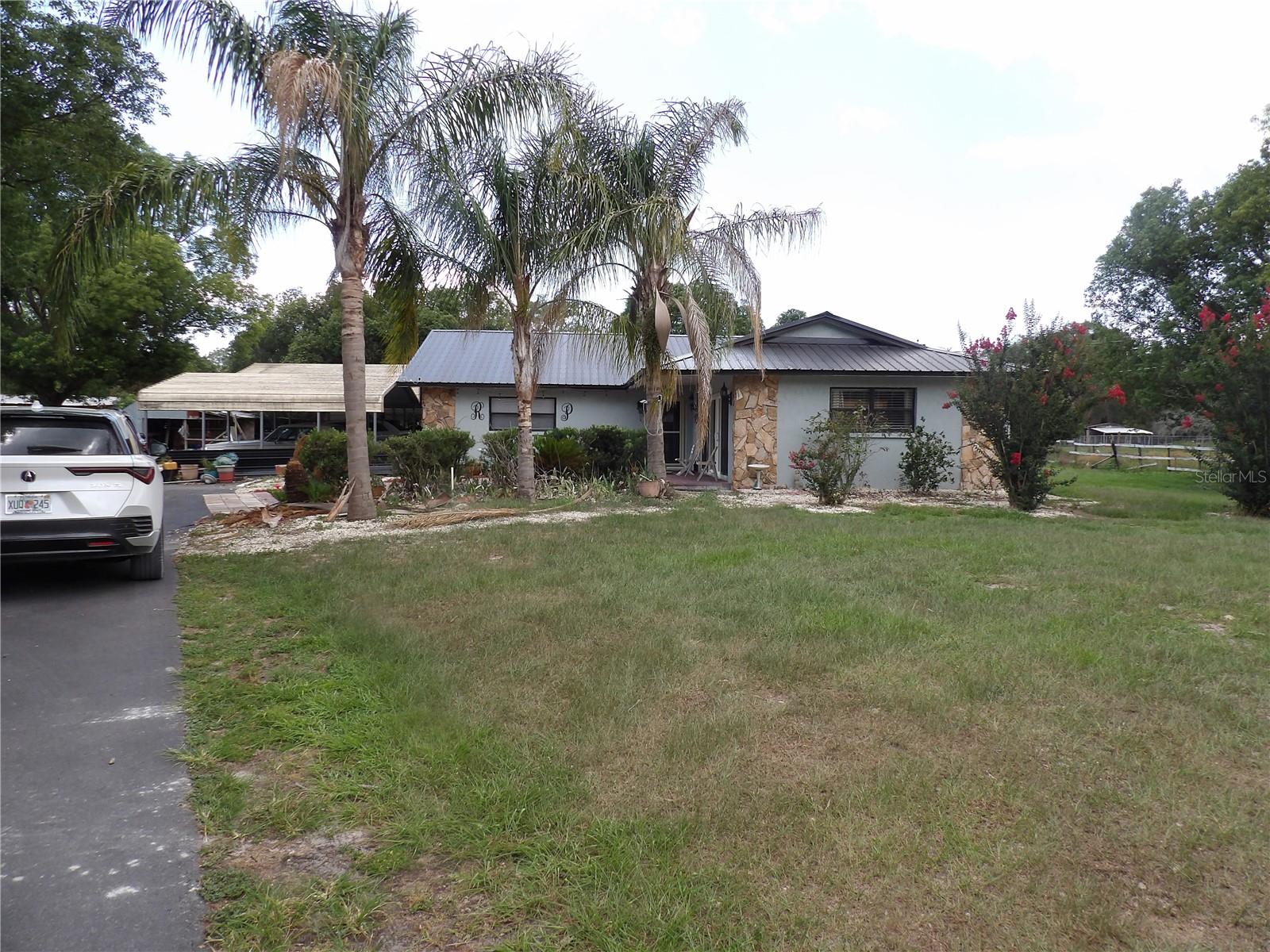There's a lot to like about this 5-acre stretch of Woodhaven Farms. The home was built in 1981 and sits under a metal roof — the kind of thing you stop worrying about for decades once it's on. Out back, there's a screened-in pool with a jacuzzi and cool deck, the sort of space that's made for slow evenings once the sun starts to drop. Inside you've got a wood-burning fireplace, tile floors throughout, and a finished garage. Outside, a shed and a detached carport give you real storage, and the property is already fenced (wood, chain-link, and wrought iron in different sections) — good for animals, gardening, or just keeping things contained. It's zoned agricultural, so there's genuine room to do something with the land, not just sit on it. Worth seeing in person to get a feel for the space.
