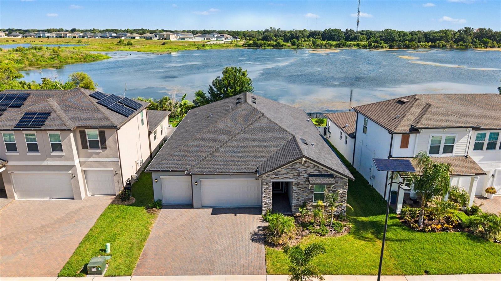 Welcome to your own slice of paradise in sought-after Triple Creek! Perfectly positioned on a quiet cul-de-sac and overlooking sparkling water, this nearly new home offers luxury, comfort, and resort-style living at its finest. From the paver driveway and spacious three-car garage to the soaring ceilings, crown molding, 5¼-inch baseboards, and stunning plank tile flooring, every detail has been thoughtfully designed. The exceptional triple-split floor plan provides privacy for family and guests alike, including an en-suite secondary bedroom and a magnificent owner's retreat. Entertaining is effortless with a beautifully appointed dry bar complete with wine chiller and a butler's pantry leading to an oversized walk-in pantry. At the heart of the home, the chef-inspired kitchen showcases endless quartz countertops, 42-inch white cabinetry with crown molding, soft-close drawers with pull-out trays, a massive island with single-basin sink, built-in oven and microwave, smooth cooktop, and stainless steel appliances. Nearly every room captures breathtaking lake views, creating a tranquil backdrop that feels like a private retreat. Step outside to the expansive screened lanai and fenced backyard, where morning coffee and evening sunsets are accompanied by cooling breezes off the water and a true resort-style ambiance. The luxurious owner's suite is a haven unto itself, featuring tray ceilings, dual vanities, a freestanding soaking tub, spectacular frameless shower, and a custom-designed walk-in closet. Guest bedrooms and baths enjoy the same upscale finishes and attention to detail. Additional highlights include impact-rated windows, a whole-home water softener, Vivint security and Wi-Fi system, in-wall pest tubes, and countless upgrades throughout. Conveniently located near shopping, dining, top-rated schools, and excellent commuter routes, Triple Creek offers world-class amenities and the lifestyle you've been dreaming of. If you've been searching for breathtaking water views, impeccable design, and a home that truly feels like a retreat, this spectacular residence is one you won't want to miss!