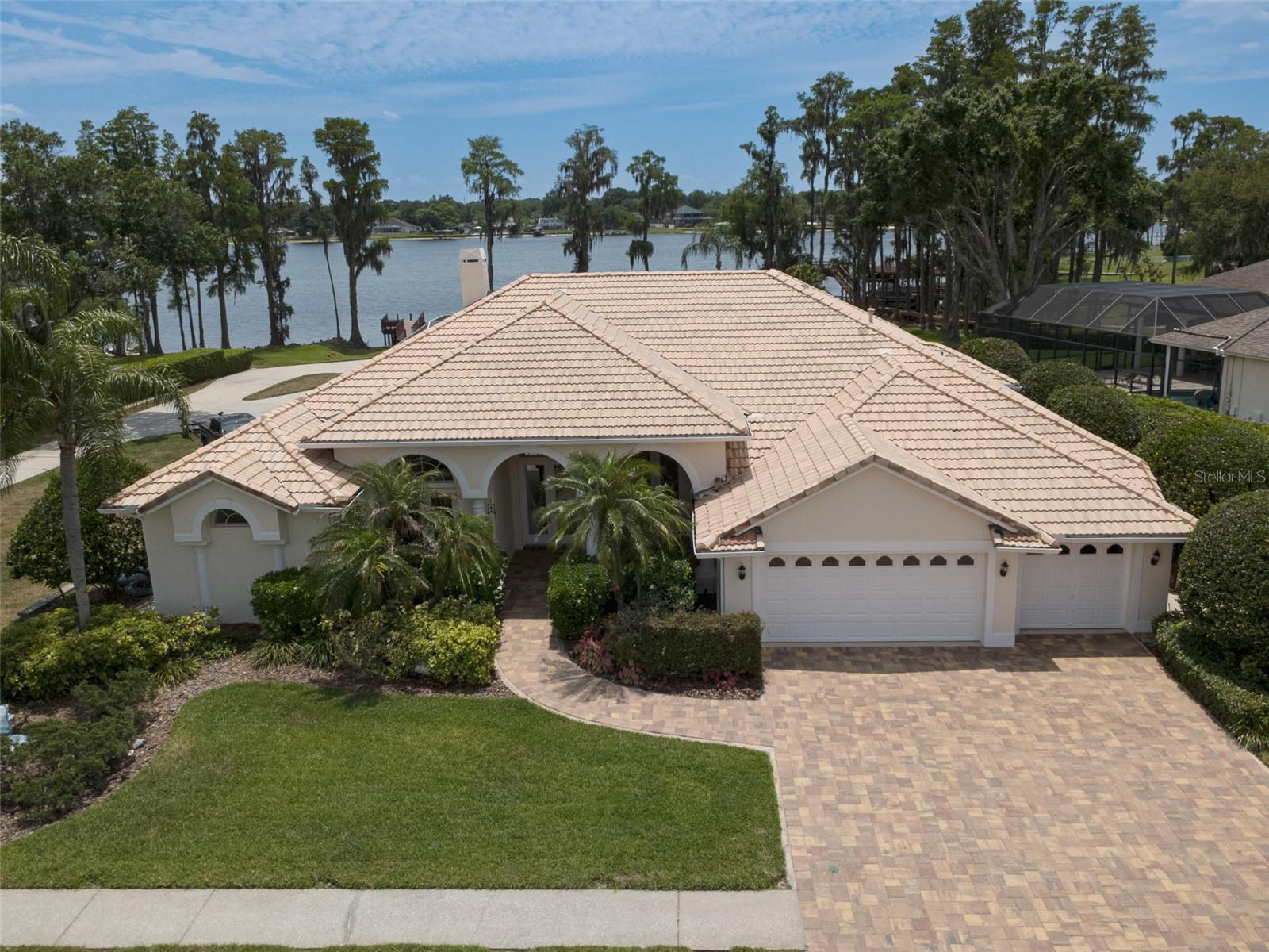 Lakefront pool home on nearly one acre in the gated Swann Lake community, featuring a private dock on Lake Padgett. This move-in ready former model home offers approximately 3,485 square feet with 4 bedrooms, 3.5 baths, and a dedicated office, all positioned to take full advantage of expansive views across the 180-acre ski lake.

Located within an exclusive enclave of just 55 homes, the property provides a rare combination of privacy, space, and direct lakefront living. Interior features include 12-foot ceilings, abundant natural light, and open living areas designed to capture the surrounding water views. The private office is equipped with wood flooring, built-ins, and direct access to the front patio, creating a functional and versatile workspace.

The open-concept kitchen includes a large island with breakfast bar seating and connects seamlessly to the family room and dining area, supporting both everyday living and gatherings. The primary suite offers dual walk-in closets, direct access to the screened lanai, and an en-suite bath with dual vanities, a soaking tub, and a walk-in shower. A secondary suite with its own private bath and walk-in closet provides flexible living options.

Outdoor living is enhanced by a screened lanai, private pool, and unobstructed lake views. The outdoor space also includes a built-in gas grill, ample seating area, and a convenient pool bath. A composite dock provides direct access to Lake Padgett for boating and other water activities.

Architectural details and upgrades include two interior 8-foot doors, four exterior 8-foot doors, a two-panel sliding glass door, a three-panel sliding glass door, and a four-panel sliding glass door system that enhances natural light and indoor-outdoor flow. The front entry features a distinctive etched crane scene on the glass door, adding a unique design element.

Additional features include a nearly one-acre lakefront lot, private dock, screened pool and lanai, whole-house generator, oversized 3-car garage with built-in storage, new pool pump, paver driveway and front porch, and its distinction as a former builder model home.

Swann Lake community amenities include gated entry, a private boat ramp and dock for residents, tennis and pickleball courts, basketball court, playground, and optional storage for boats and recreational equipment.

Conveniently located in Land O’ Lakes with access to major highways, shopping, dining, and schools.

Opportunities like this—combining lakefront access, privacy, and a thoughtfully designed home—are limited. Schedule your private tour to experience the setting, space, and lifestyle this property provides.