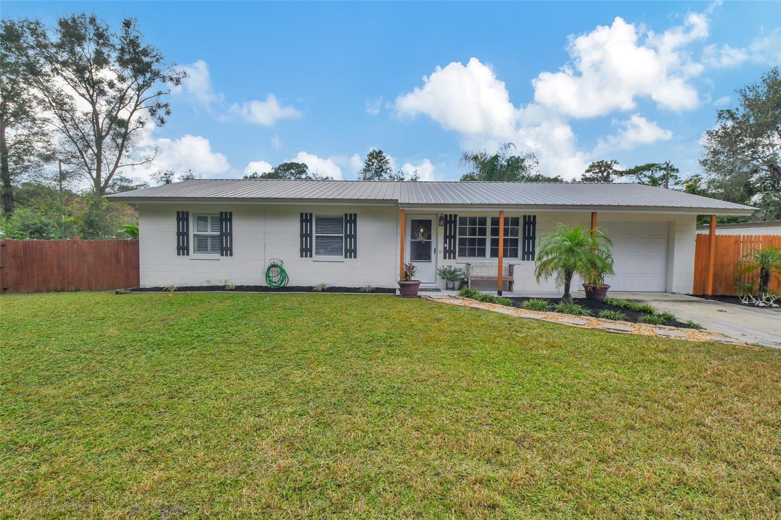 Welcome to this charming and updated block built single-family home nestled in the heart of De Leon Springs. This cozy ranch-style property offers a comfortable and inviting atmosphere, perfect for those seeking a peaceful retreat. METAL ROOF 2017.  Step inside this 2 bed 1 bath home, and be greeted by the waterproof luxury vinyl plank flooring that flows seamlessly throughout. The open living and dining area are bathed in natural light, creating a warm and welcoming ambiance. The updated kitchen boasts a stainless refrigerator, gas range, hickory cabinets with soft close drawers, and Corian countertops for food prep. Dining area offers a hutch with coffee bar counter. The primary bedroom features a walk-in closet, window bench with storage, and built-ins, providing ample space for all your belongings.  Updated bath is spacious with double sinks, step in shower and lots of storage shelving. Open the Dining Room slider to relax and unwind on the large covered screen enclosed porch, measuring an impressive 38x12. Gather with friends and family on the 18x18 paver patio complete with a charming fire pit. The fire pit adds a touch of elegance to your outdoor gatherings, while the fenced yard provides privacy and security. Additional amenities include room for 5+ cars between the attached 1 car garage (which is vented with air), a detached workshop and detached garage, both could house an additional 2 cars or perfect for storage or hobbies. A he/she/they shed in the backyard needs some updating but offers endless possibilities.  Well house has storage for lawn equipment. Conveniently located near DeLeon Springs State Park, this property offers the perfect blend of tranquility and accessibility. Don't miss out on the opportunity to make this house your dream home. Schedule your private showing today! Audio/Visual Surveillance with Ring Doorbell.