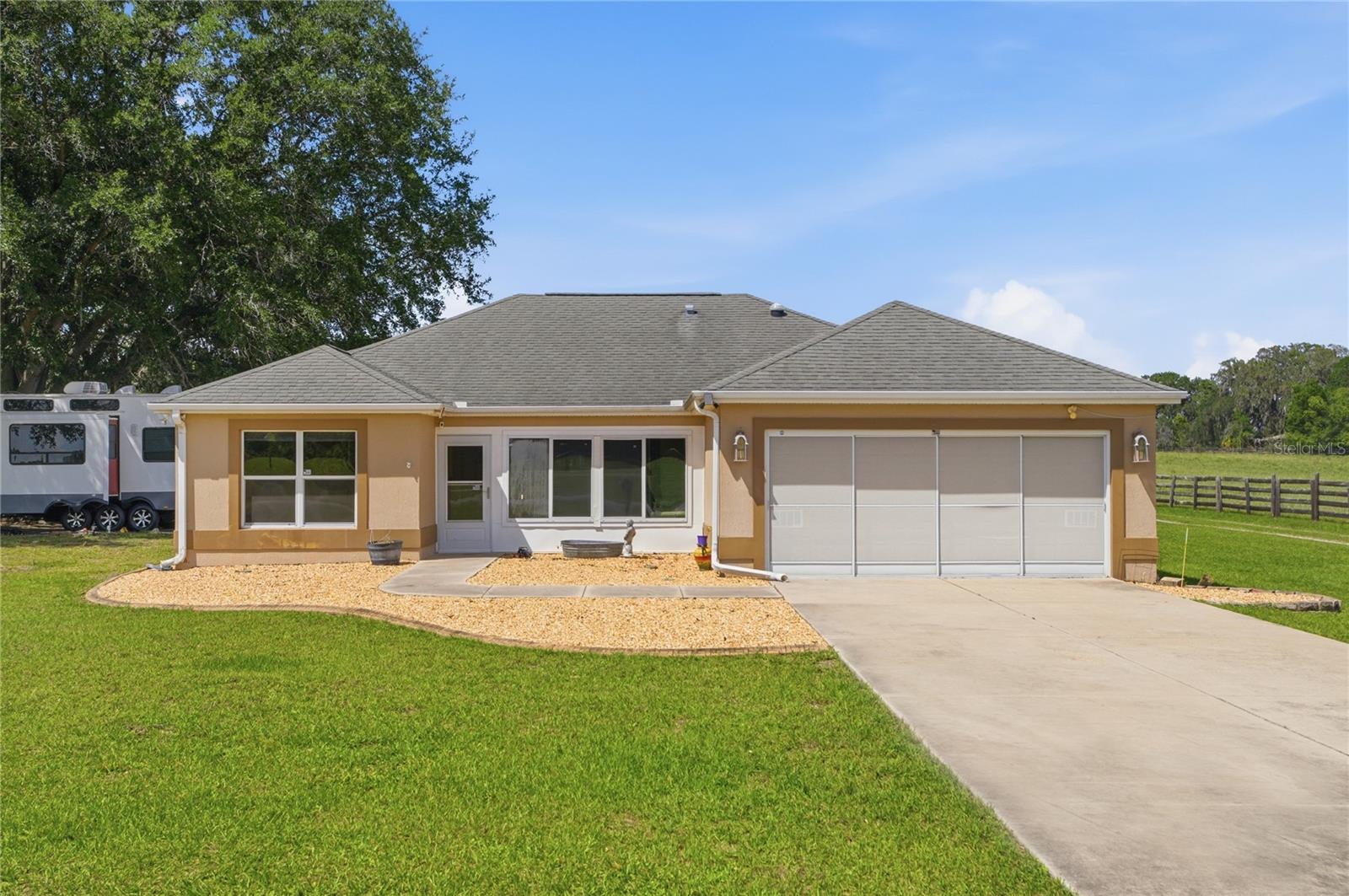 Rustic Allure Meets City Convenience! Charming 3/2 Concrete Block & Stucco Custom Home with a 2 Car Garage including sliding screen doors, a 20 x 23 Carport, and an additional 20x 20 Detached Garage on a 1 Acre Lot with ROOM FOR A POOL, You are Neighbors with The Villages, and The Villages Lifestyle, located close to Lake Sumter Landing, Spanish Springs Town Square, an Abundance of Shopping, Restaurants, Oxford Downs, Browns Country Market, Banks, Medical, and More!  Currently an Income Producing Property.  HVAC 2021!  No Carpet!  The lovely Enclosed Front Porch greets you before entering into the main home, which offers an Open Concept floor plan, with the Living area featuring Vaulted ceilings, and Glowing Laminate flooring.  The Living flows to the Dining area which provides a Stunning Designer Chandelier, and access to the Bonus room featuring Tile flooring, and access to the Lanai, a Fantastic Additional Living Space!  The Open Kitchen showcases a Solar Tube, Stainless appliances, Granite Countertops, White Wood Cabinetry, Generous Breakfast Bar, and an Upgraded Light fixture!  The Split Floor Plan offers the Utmost Privacy for both the Owners and their Guest, with the Primary suite commanding one side of the home while the guest bedrooms and guest bathroom are located on the opposite side of the home!  The Primary Suite boasts Private Access to the Lanai, a Walk in Closet, and an En Suite bathroom providing a 2 sink vanity, and a Walk in Shower.  The two additional bedrooms feature nice size built in closets, offer your guests Convenience, and Plenty of Space!  Enjoy Outdoor Florida Living on the Large 23 x 12 Screened Lanai, Great for Outdoor Dining or Relaxing in your Own Private Paradise filled with Tropical Breezes, Beautiful Sunsets, and Peaceful Living!  Spend Evenings around the Campfire gazing at the Unencumbered View of the beautiful Starry Nights!  Well Replaced 2025, Septic Pumped 2024, Detached Garage 2023, Screened Lanai 2023, Roof 2016, Carport 2014, Water Heater 2015.  A True Country Setting with All The Convenience of The Villages Lifestyle!  Call Me Today For A Private Showing!