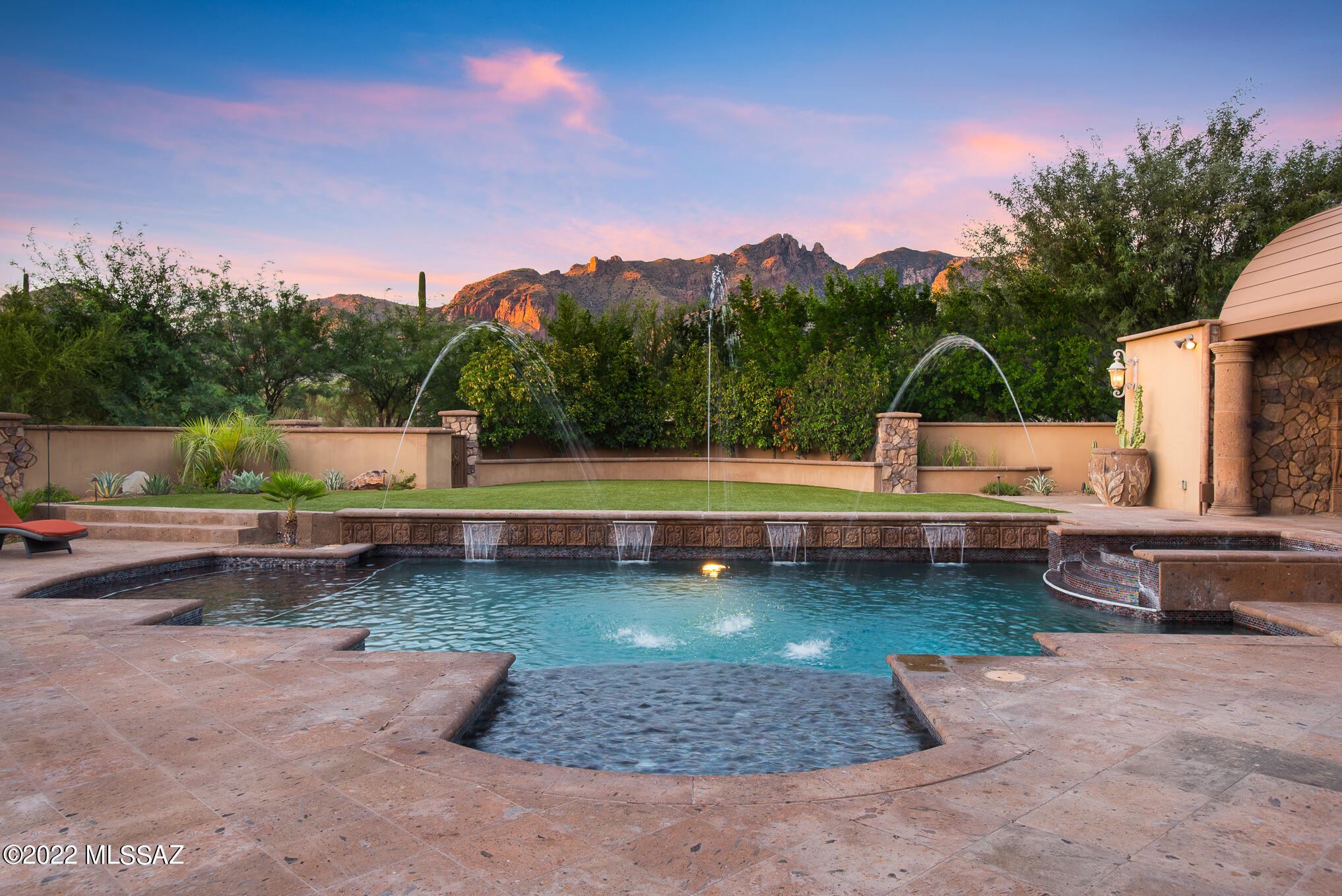 Exquisite 2009 masonry-built custom home w/ commanding Catalina Mountain views, situated on a private 1-acre lot at the end of a cul-de-sac in coveted guard-gated La Paloma Estates. This sprawling one-level residence combines old-world charm w/ flawless execution of the finest finishes & materials completed w/ extreme attention to detail. This home is a work of art defined by luxury, quality & craftmanship Driveway & large motor court lined in pavers leads to four garage spaces & a gated courtyard. Upon entry, an unforgettable visual experience greets you w/ an automatic retractable sliding glass door merging the indoor & outdoor spaces seamlessly and showcases the extraordinary setting outside. Formal living room & dining room w/ natural stone flooring inlaid w/ wood..CONTINUED-CLICK MOR Cantera stone gas fireplace, wood-beamed ceiling, custom paint treatments, built-in cabinets & shelving is designed for large-scale entertaining. Stunning powder room off entry for guests. Impressive wine cave w/ dedicated temperature control, custom iron door & storage for 100's of bottles of wine is adjacent to the formal dining room. Distinctive gourmet kitchen w/ oversized center island has one-of-a-kind hand-carved custom cabinetry, prep sink & 2 beverage coolers. Beautiful granite counters & high-end appliance package that includes Sub-Zero, Wolf, Asko, Miele & Fisher Paykel. Farm sink w/ large window provides sensational mountain views. A huge skylight over the center island & a wall of windows at the breakfast table infuses natural light throughout the space. Unrivaled Butler's Pantry supplies extra storage & features custom cabinetry w/ built-in shelves, granite countertop, sink & drawer dishwasher. The kitchen is open to a warm & inviting family room that lends itself to everyday living. Adjacent to the family room is a dedicated media room, a full bath w/ a shower & a big recreation room w/ a wet bar & a gas FP. A sliding glass door from the family leads to the resort-style backyard & an outdoor living room protected by the depth of the covered patio & the Cantera stone fireplace. As the patio wraps around the house it delivers a Built-in BBQ, an outdoor dining area & a wet bar outfitted w/ a beverage cooler. Enormous metal ramada w/FP houses a storage room & a half bath. The centerpiece of this remarkable outdoor space is the pool, spa, fountains & dramatic deck jets. On the east wing, luxury defines the spacious master suite w/ hardwood floors, Cantera stone gas fireplace &  French doors to access the patio. Richly appointed master bath displays intricate hand-carved cabinetry at the two separate vanities, granite counters, huge glass-enclosed shower, soaking tub & see-through gas fireplace. Oversized his & hers closets have an uncommon level of custom built-ins, glass-faced cabinets & built-in island dressers. Office/den in the master wing w/ coffered wood ceilings & extensive woodwork is loaded w/ character. On the west wing, four additional en-suite bedrooms w/ substantial walk-in closets. Each bathroom has a unique design w/ high-quality materials. The fourth en-suite bedroom, the "casita", has a separate entrance, Cantera stone gas fireplace & is outfitted with a wet bar area w/ a sink, microwave & refrigerator.