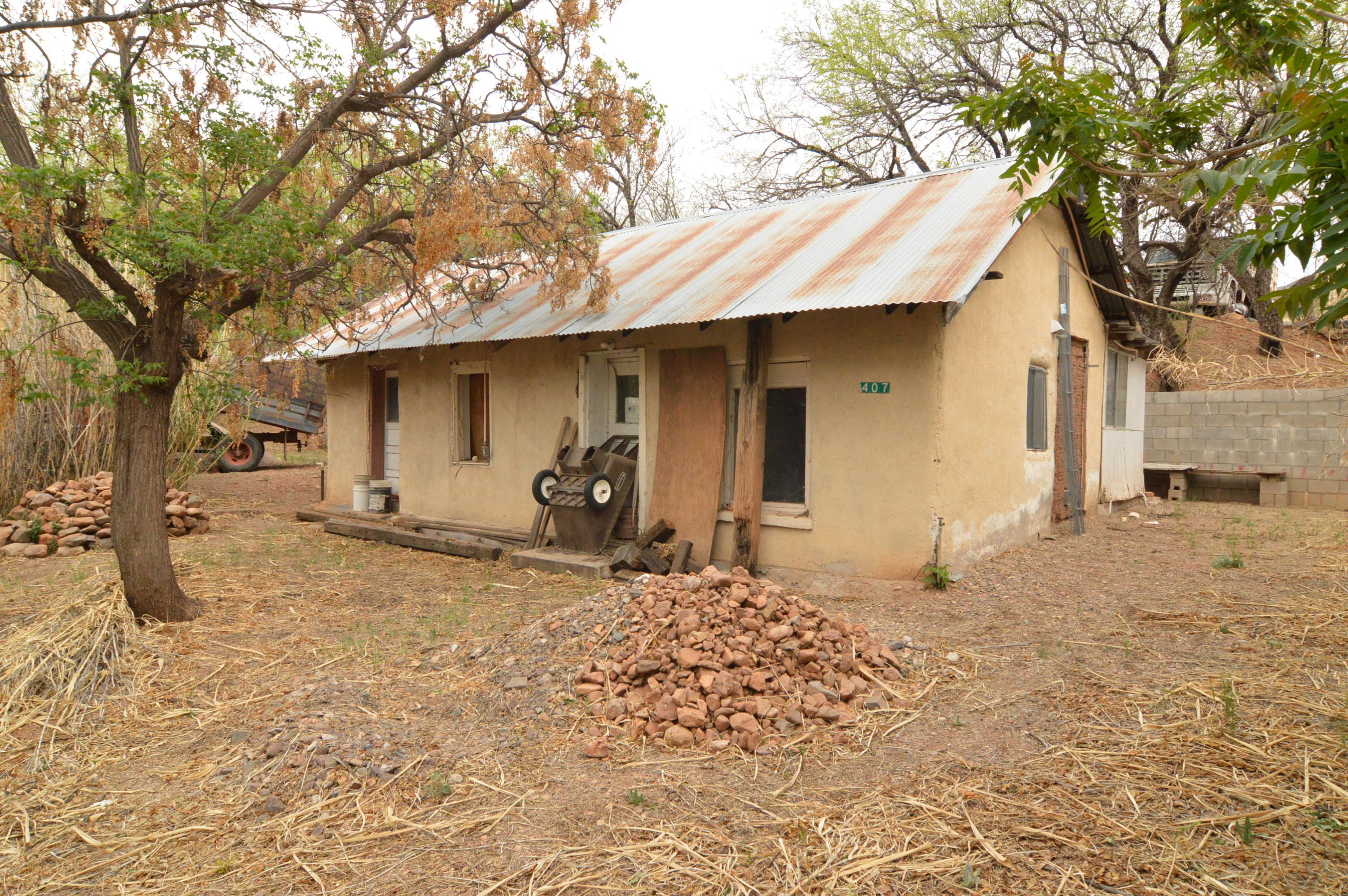 Ultra-rustic adobe bungalow c.1915 on appx one-half a Town Lot. This tiny 842sf residence REQUIRES COMPLETE RESTORATION by one who appreciates authentic old homes & is looking for a worthy labor of love ~as has been done to the easterly-situated, very charming, neighboring home. Nestled against the hillside of a wooded, very quiet alley in the SW part of historic Patagonia, interest in restored/restoring properties of this type for a private residence or Air B&B-type rental is soaring. Inside are 4 separate rooms: Be, Ba, Kit/Dining + Living, all of which have doors to the outside. At a later date, a tiny Mud Rm/Lndry was added. Very little remains of the Kitchen & everything needs restoration.  Variably, there's room for a sm circular drive, Garage/CP, sitting/garden area or RV parking.