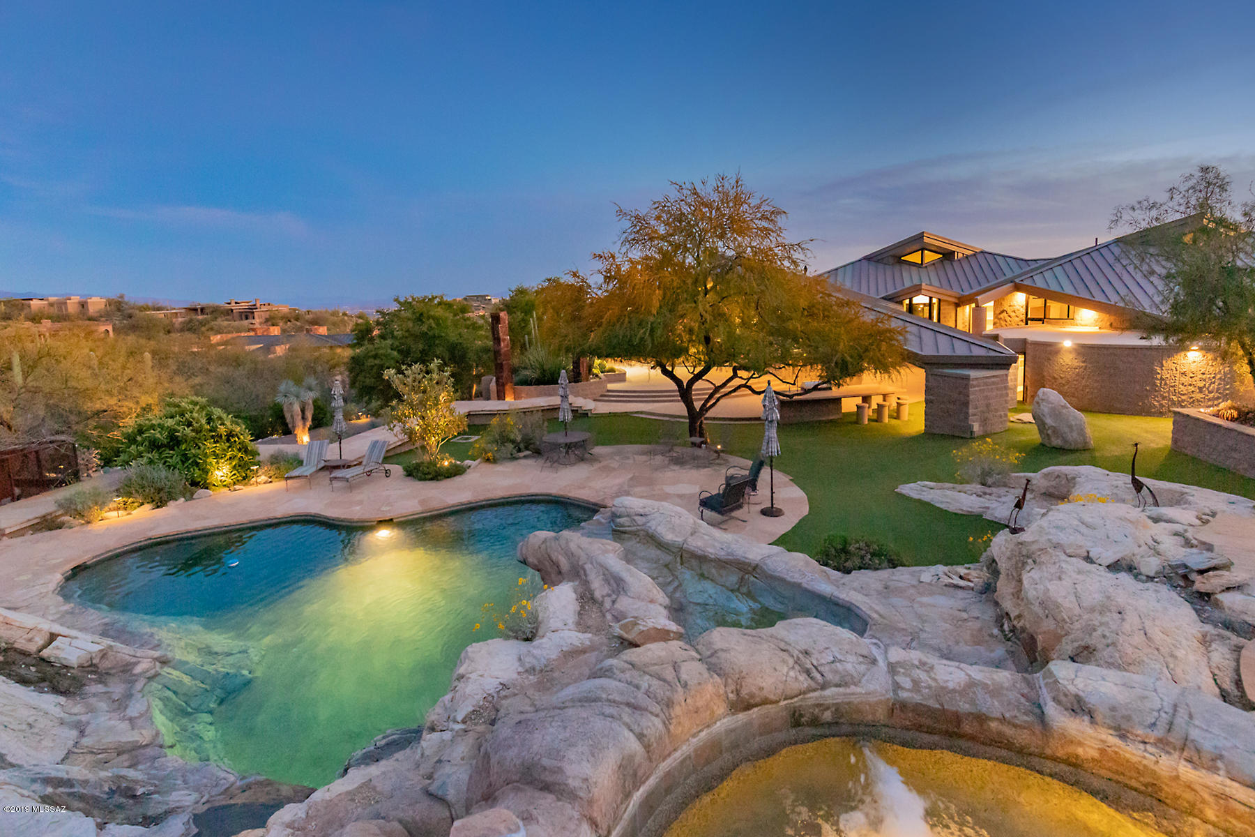 This contemporary, unrivaled architectural masterpiece in the exclusive gated community of The Canyons is situated on a peninsula w/long private drive to covered portico. The fluent floor plan offers unparalleled city and mountain views unlike any other, w/complete privacy to entertain to your hearts content. This 7080 Sq. Ft. grand estate is a fully self-sustainable compound w/private well, solar panels, orchard & vegetable garden. Ideal for easy living, this rare offering includes elegant living room,  dining room, gourmet kitchen with SS appliances &  Caesarstone quartz counters. Master suite features lavish city views, enormous walk-in closet,  large ensuite and vanity area.  Nestled in lushly landscaped backyard is  pool/spa w/artificial turf, large pool/spa, waterfall & ramada.