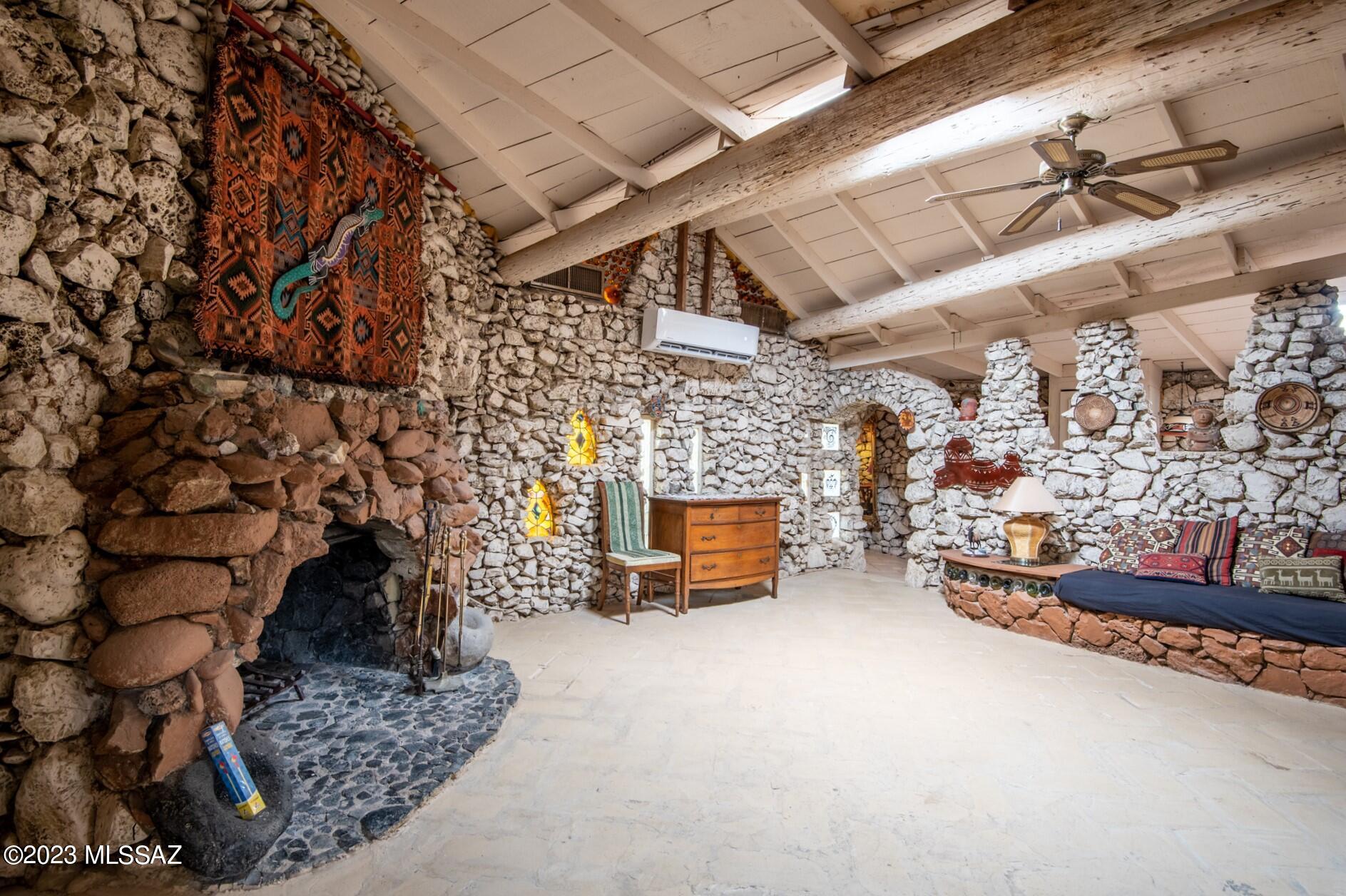 A timeless structure, insulated by thousands of glass bottles of various array creating a colorful glow, nestled between stones and full-sized wooden beams at the ceiling. You must see it to believe it! This alternative constructed rock and bottle home, has a guest cottage, an outdoor kitchen, and over 2000 sq ft of arched passageways of hand-crafted old-world charm! Concrete and flagstone flooring are the foundation, featuring three deep-rock fireplaces, and two wood-burning stoves. Hidden nooks such as the two alcoves for reading, can be used as an office, a library/ study, (alcoves were originally created for accommodating as a bedroom). Built-in concrete furniture throughout, and a circular dining room table, studded with slices of cholla, and saguaro rib lined cabinets... ...and saguaro lined cabinets surround the dining room. A king-size concrete platform for a bed sits next to one of the three rock fireplaces in the main room. A concrete couch lines the rock wall in the living room, (just add cushions and pillows). Technically this home is considered a 2 bed, 3 bath property, (a separate bathhouse serves as the 2nd bathroom) with a cottage that also accommodates two queen sized cement platforms for additional beds. Adjacent to the cottage is an outdoor covered kitchen and workshop complete with a full-size custom cement cast pool table. Along the many cement and rock lined pathways of this 2.53 acres estate, you will find dates and artists handprints etched starting from 1964. Once operated as a bed and breakfast or Airbnb. Brand new foam insulated roof and two new mini-splits installed in 2023 on the main structure. (two additional parcels can be purchased adjacent to this parcel for a total of 4.51 acres)!