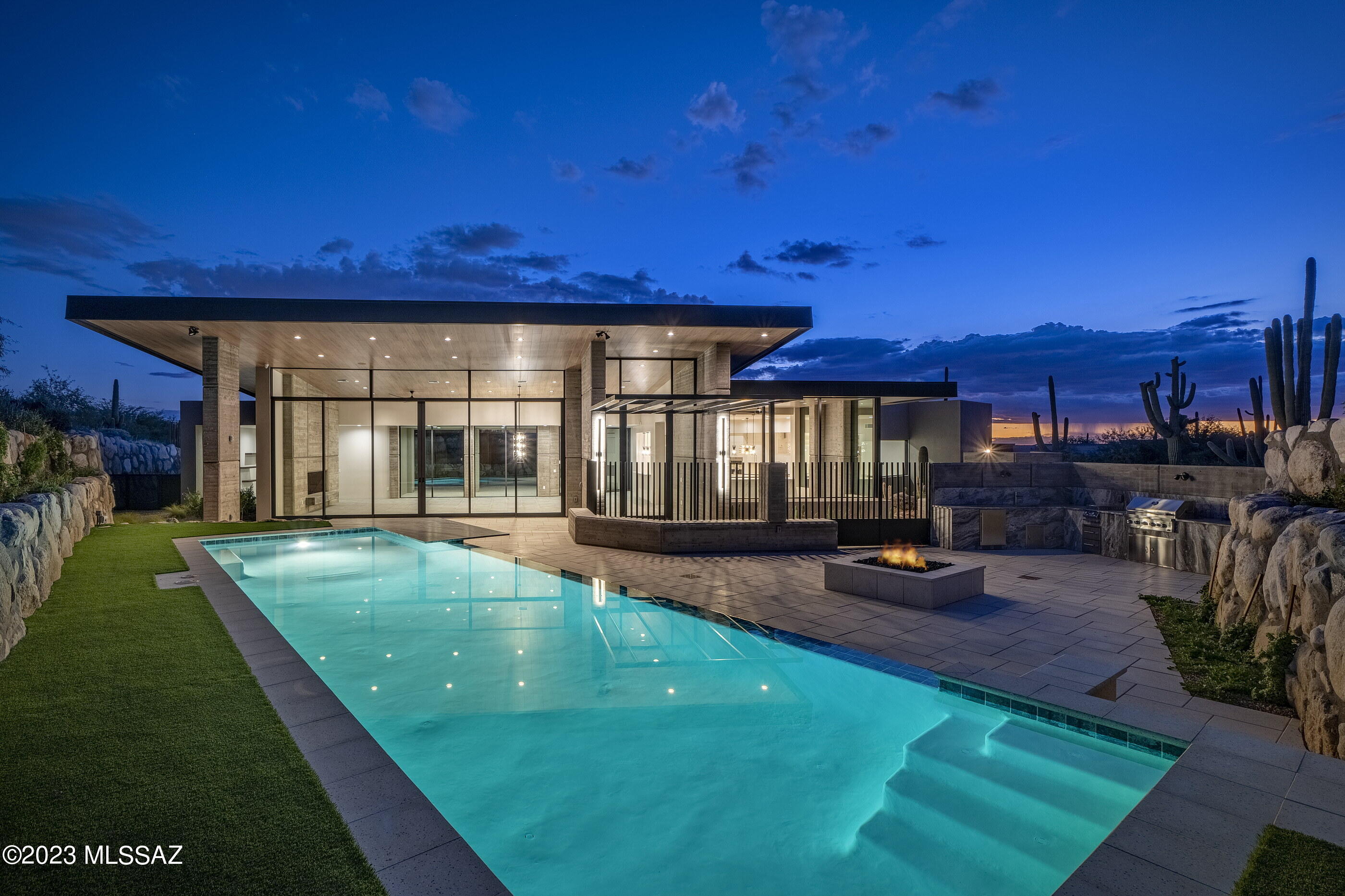 Located in the prestigious Pima Canyon Estates community, one the finest private communities in the Southwest and situated behind the secondary gates of Pima Garden lies a unique opportunity to own this incredible new construction, Kevin Howard designed Desert Contemporary, built by master builder Monty Bartholomew. A 5,677 square foot residence offering five bedrooms, all of which are ensuite, and six bathrooms. Large open public spaces flow through the property allowing for seamless connection points with indoor and outdoors transitions that spill out onto numerous covered verandas. As one travels between the individual spaces, dramatic landscapes unfold expressed through floor to ceiling walls of glass, allowing for an abundance of natural light filling every room. From sunrise to sunset, the interplay of light and shadow shifts, acting in concert with the home, illuminating and complementing the materials on display. This estate home features two pools on property, with an integrated spa, strategically placed just off the primary suite, taking full advantage of the unparalleled privacy and striking view corridors, while being completely nestled within the lush natural vegetation of the Sonoran Desert.

Expansive cantilevered roof lines produce a strong graphic, while responding to nature's elements and enhancing the quality of the user experience. Retractable "Fleetwood" glass walls, with seamless flow from the interior of the great room to exterior patios, extends the outdoor living floor space, combining both significant spaces for entertaining, as well as thoughtfully designed intimate spaces, for comfortable everyday living.