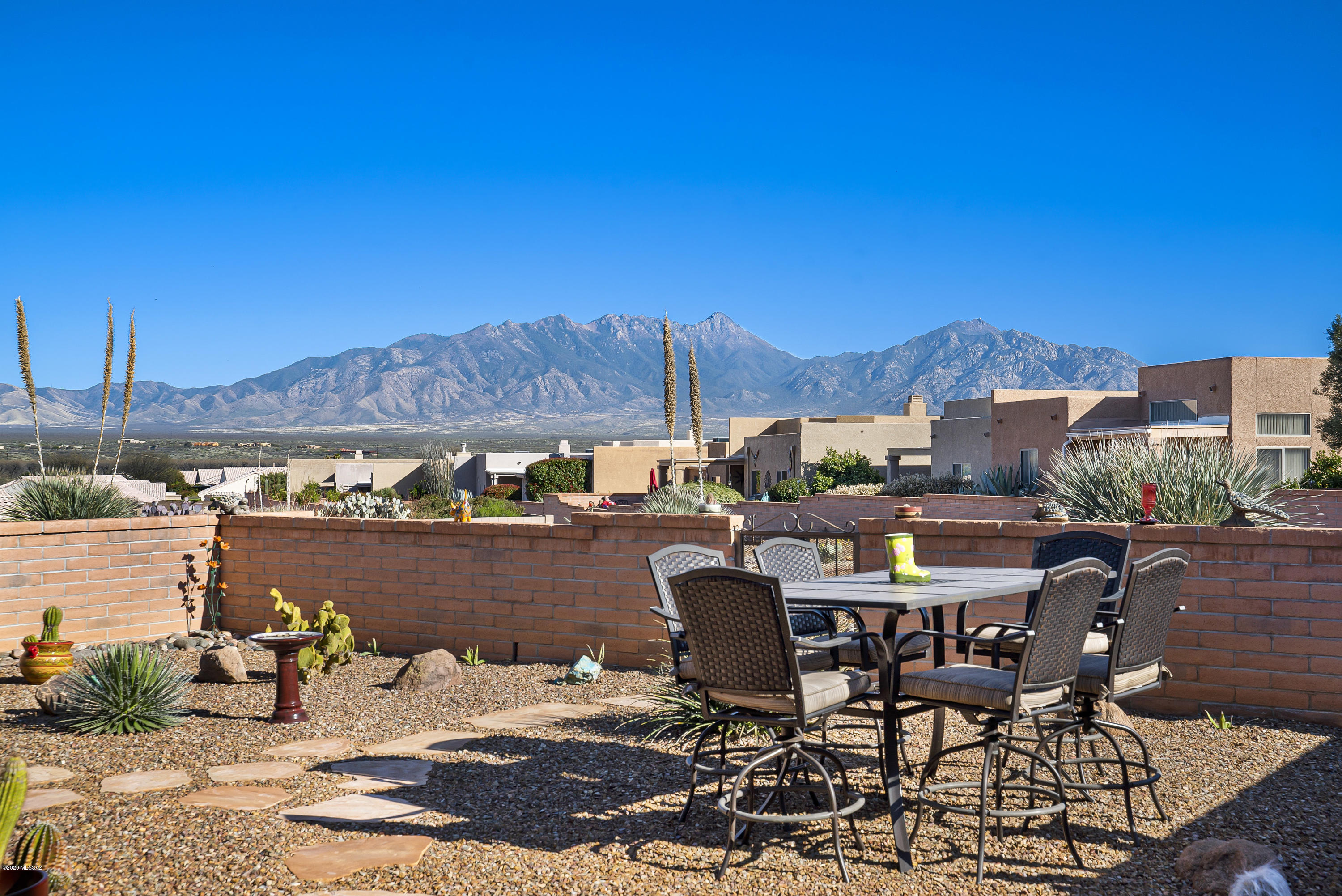 An array of desert cacti provides easy care landscaping and pleasing curb appeal.  The expansive living room has stone look tile flooring and incorporates an open space dining area neatly tucked in the corner.  High ceilings make it feel spacious and the transom window delivers warm radiance above sliding glass doors which lead to the covered patio.  The kitchen features white cabinets, stainless appliances, a serving bar, eat-in breakfast nook, and a sweeping archtop opening allowing you to chat with folks in the living room.  Double French doors lead into your large master suite which also has a patio door offering you the opportunity to step outside to view the amazing stars at night.  A large backyard with extended paver patios provides you will several options for enjoying terrific views of the Santa Rita Mountains.  You'll also look forward to the end of a busy day to relax on your patio to watch the changing colors in the sky and the stars begin to shine high above.