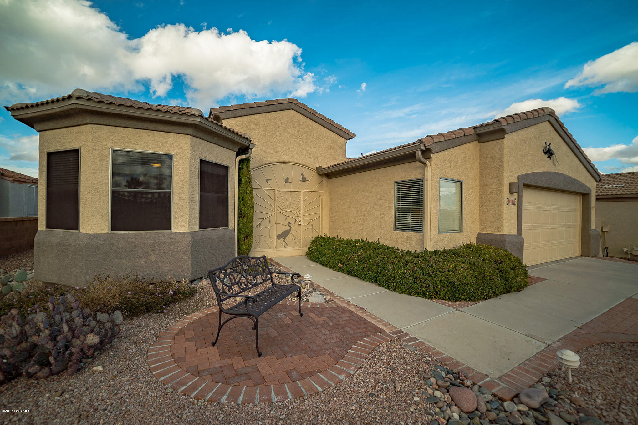 You'll find amazing mountain views from the walkway and sitting area as you arrive at this gorgeous home in Canoa Ranch. As you pass through a screened in breezeway to the double door entry, you'll be struck by a wall of windows that infuse radiance and desert vistas into the great room while bringing out rich tones in the beautiful floor tile throughout the entire home. To your right is a multi-purpose room which can be used as a formal dining room, quiet den, library, office or inspirational art studio. The easy serve island kitchen features a walk up snack bar with a prep-sink, making it easy to accommodate the dining area. The rich wood cabinetry offers an elegant contrast to the light tile backsplash, counter tops and stainless appliances. Your master bedroom suite is dressed with  a cozy bay window while the diagonally laid floor tile leads you into a luxurious bath with double sinks and a beautiful walk in glass and tile shower. And, the guest bedroom has a cove bay window displaying neighborhood views. Relax on your back patio with its flowing red brick pavers and surrounding cactus islands that create a botanical backyard journey with miles of desert landscape views. The 2.5 car garage has plenty of room for your golf cart or workbench and garage cabinets. Lots of energy efficient items including aerofoam in attic, solar attic fan, tankless water heater and also a capacitive deionization softener.