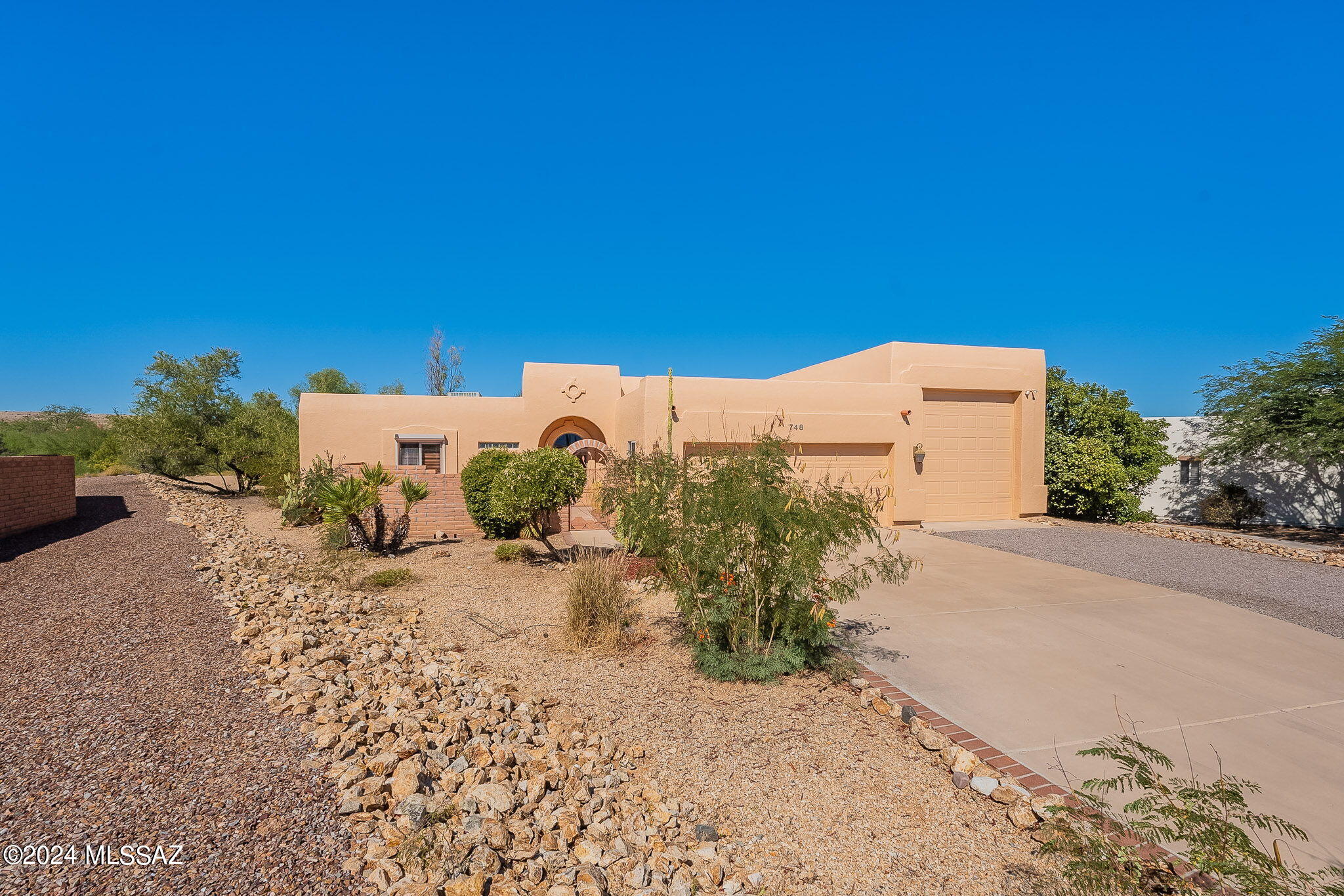Located in the desirable Portillo Ridge neighborhood, this beautiful Santa Fe home, crafted by Pearce Homes, combines comfort and elegance with stunning mountain views. Enter through a charming front courtyard that offers vistas of the Santa Rita Mountains. Inside, you'll find gorgeous tile flooring and a versatile space ideal for a home office, den, or study. The home boasts fresh interior and exterior paint and brand-new luxury plank tile flooring in both bedrooms. The kitchen is a standout, featuring quartz countertops, two-tone cabinetry, a built-in hutch, and a spacious pantry. Relax in the guest bathroom with a hydrotherapy walk-in tub, and retreat to the primary suite with direct access to the enclosed Arizona room. The Arizona room, lined with French doors for abundant natural light, opens up to a desert-landscaped backyard with a pergola, pavers, and a unique outdoor shower. The property also features a rare RV garage with full hookups, storage cabinets, and a sink. The washer and dryer are conveniently housed in a closet within the garage. Enjoy access to Green Valley Recreation amenitiescall today to schedule a tour of this exceptional property!