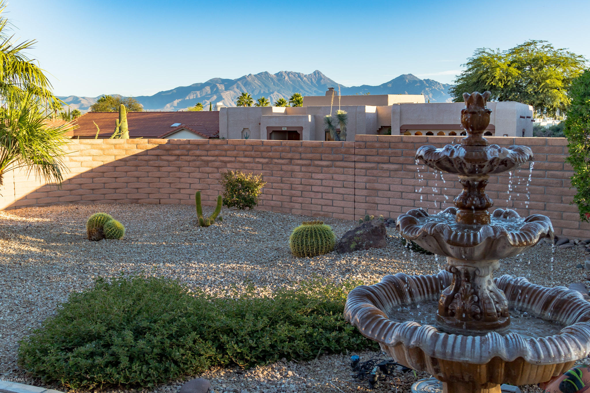 Nice curb appeal with a grand entryway, large pillars and accented arches on a covered front patio. Step inside and you will notice the oversize tile flooring set on a diagonal delivering a contemporary look. A serene living room with vaulted ceilings, a cozy corner fireplace and a 3-panel sliding door offer delightful backyard views. The den, complete with murphy bed offers versatility in use for extra guests. The “U” shape kitchen design means you’ll have more room to work while surrounded by high quality cabinetry, stainless appliances and a gas cooktop range that combine to create culinary delight. And, the smooth Corian countertops along with an integrated sink make cleaning up quick and easy. The breakfast bar offers a convenient way to serve a quick snack and the breakfast nook with backyard views is perfect for coffee and conversation. For more formal dining, there's a roomy dining area that opens to the family room. A generous master suite with patio doors offers access to the backyard. The master bath with heated flooring has a jetted corner soaking tub, a walk-in glass block snail shower and beautiful desert color tones that come to life from a ceiling light soffit and a skylight. Outdoor living is a wonderful experience and the large covered patio will make a perfect place to entertain guests, plus an extended brick patio flows out to additional sitting areas, a trickling fountain, desert landscaping and miles of gorgeous mountain views.