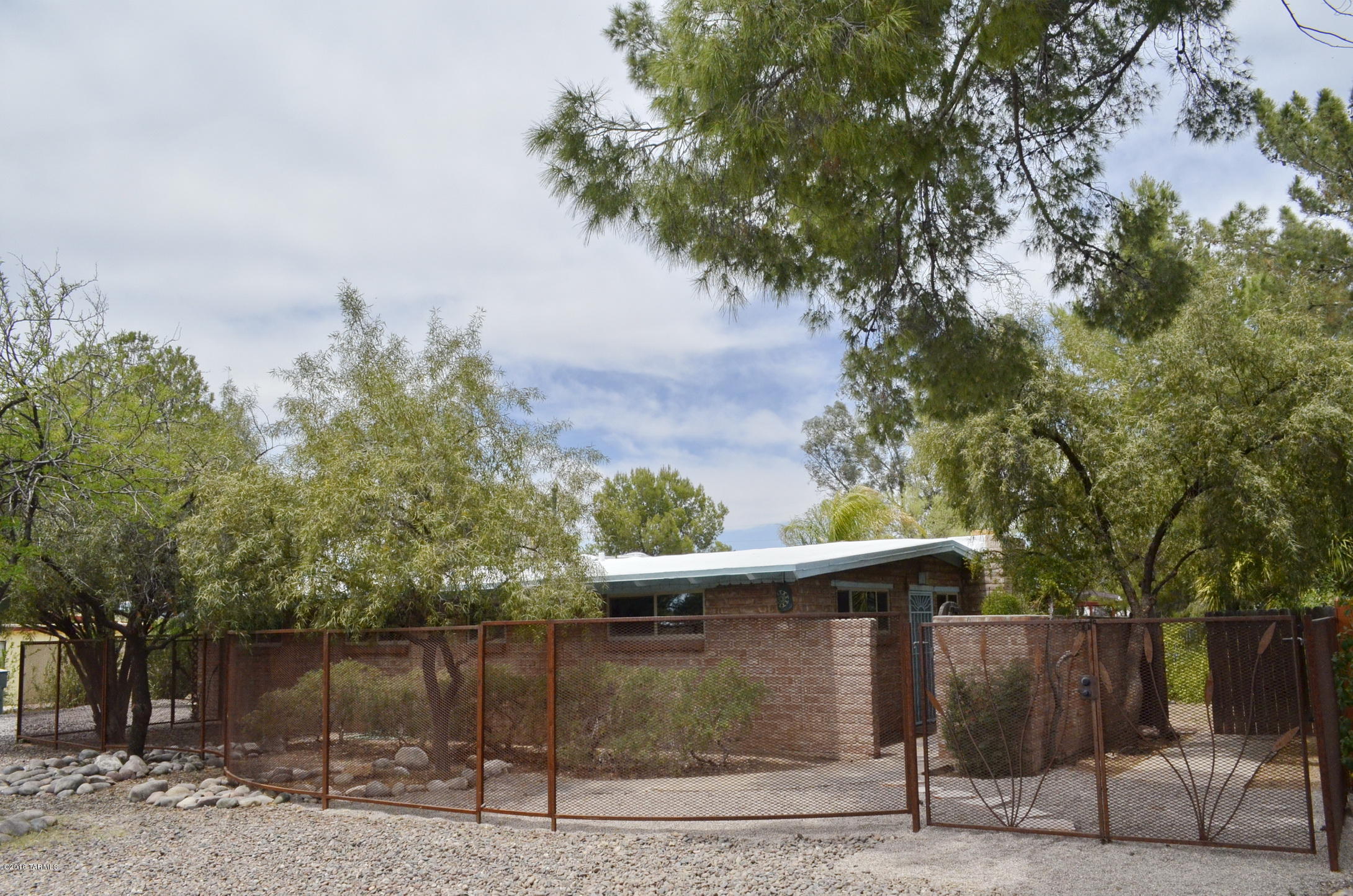 Hacienda charm with guest quarters on large, shaded lot. 3BD/2BA main house features wood beam ceilings, fireplace, Mexican tile kitchen and bathrooms, stainless appliances, saltillo floors, skylights, ceiling fans, new energy-efficient windows, new high-efficiency heating and AC, dual cooling, three shade porches, generous bonus room for office or shop that is heated and cooled, secluded courtyard. Renovated 560 sq/ft guest quarters have new kitchen, full bath, laundry, and private back yard; could be used as master suite or 1 BR separate entry rental unit. Enjoy the sparkling pool in spacious private backyard oasis with mature shade and citrus trees.   This home has been well maintained and won’t last!!