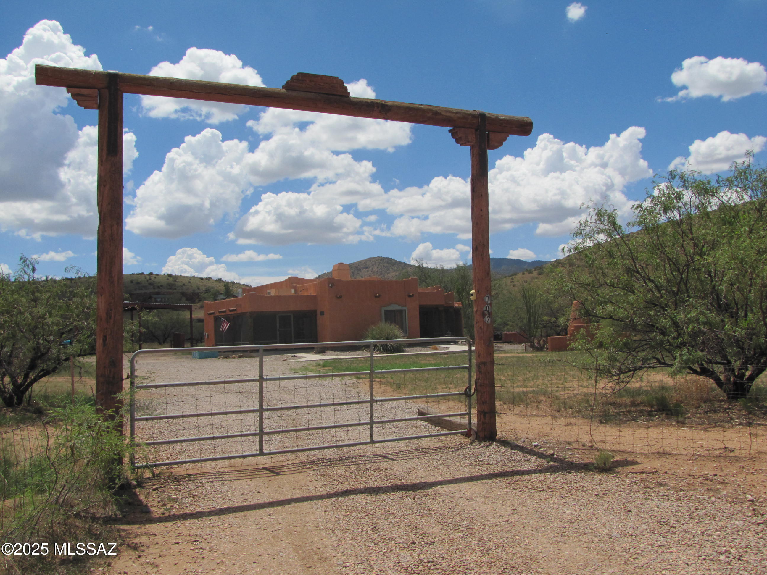 Near the foothills of the Dragoon Mountains!  This custom-built 2BR/2Ba stucco home is on 10 fenced acres. Custom doors and cabinets throughout. Both BR have a bathroom, walk-in closet and door onto screened side patio. Open floor plan with exposed beam construction. Dining area has built-in hutch; kitchen has built-in rack for glassware above island/breakfast bar & pantry. Door leading from dining room outside toward carport. Laundry room next to kitchen has W/D, shelving and a window. Front patio, outside LR, is also screened.  Outdoor fireplace & covered outdoor spot for BBQ. Hot tub just off the side patio (sold as-is). Large 20x30 metal shed; additional shed holds pressure tank for 3000 gal tank holding hauled water. Covered RV parking w/full hook-up. Located 4 miles from  Sunsites.