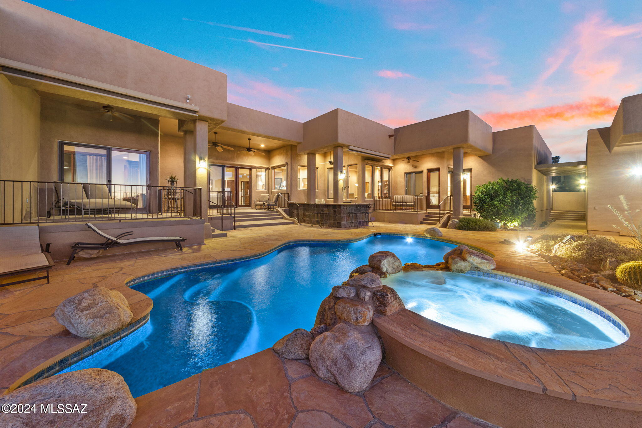 Nestled within the prestigious gated enclave of Eleven Arches Estates, this exquisite Soloway Designs home epitomizes luxury desert living at its finest. Boasting meticulous landscaping adorned with flourishing fig and citrus trees, the grounds offer a serene retreat while requiring minimal maintenance, allowing you to indulge in the quintessential Tucson lifestyle. Step inside the main residence to discover a space designed for both relaxation and entertainment. The airy and inviting great room, complete with a cozy fireplace and soaring ceilings, provides an unparalleled backdrop for gatherings, offering sweeping vistas of city lights, breathtaking sunsets, and majestic mountain ranges that stretch as far as the eye can see. 
The gourmet kitchen is a culinary enthusiast's