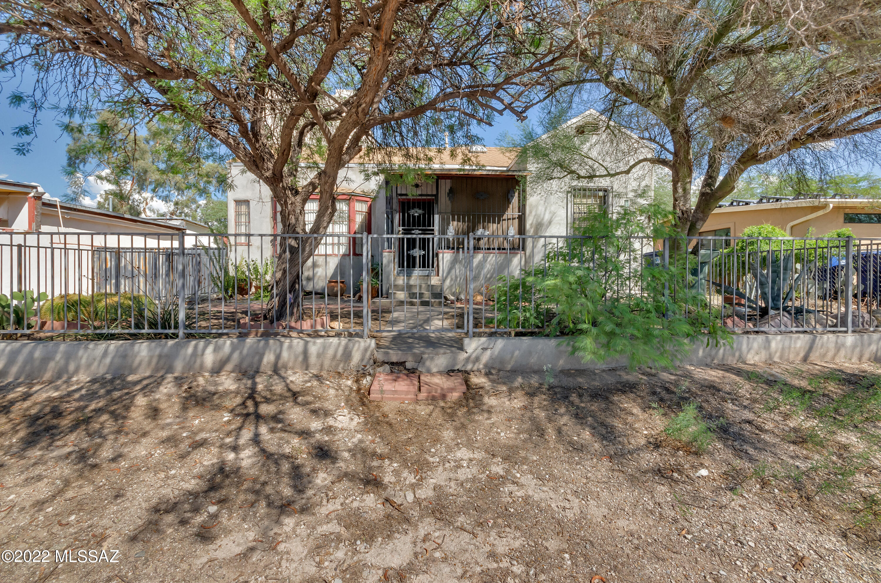 The original home is charming but needs cosmetic work; already has improvements-updated bathroom, ceiling fans in living room & both bedrooms, new HVAC installed about 3 years ago (2019) and the roof is less than 5 years old. The floor is the living room is real wood. The front covered patio is enclosed with lovely ornamental wrought iron. The non-completed addition (not counted in sqft) has so much potential-just use your tools and imagination. This addition has most recently been used for storage. The property is fenced and the front of the home has lovely vegetation. Large R2 lot with room to ''add on'' or build. No HOA. Fantastic central location near shopping, bus lines, University of Arizona (less than 3 miles), Banner-University of Arizona Medical Center (less than 2.5 miles), Pima Community College-downtown campus and I-10. Sold AS IS-owner will not be making any repairs.