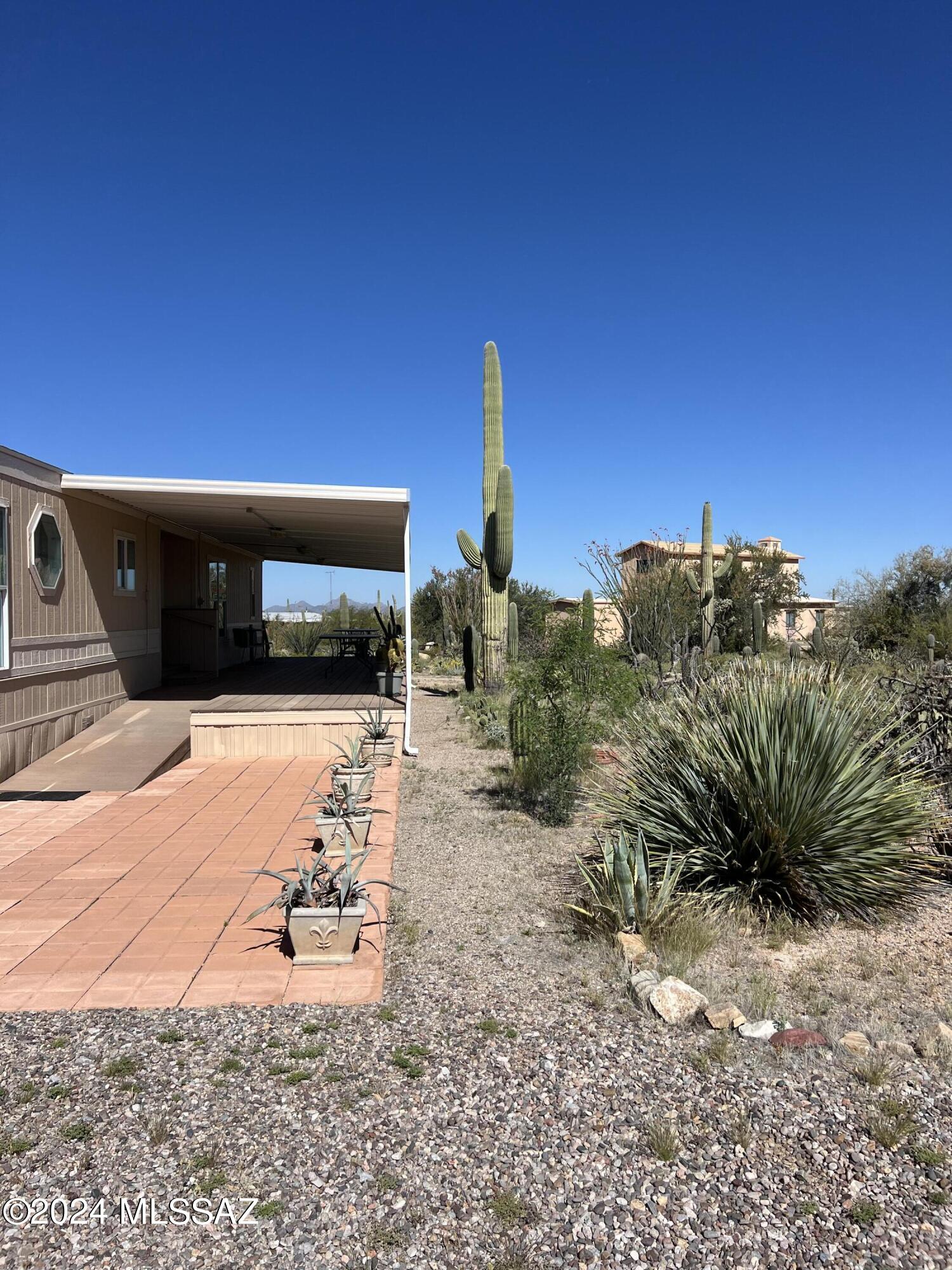 VIEWS all around located by Saguaro National park west. This unique 4.23 acre property combines comfort and versatility. Enter the charming living area with new carpet and vinyl plank flooring. Leased propane for gas range , ample wood cabinetry, a breakfast bar and pantry closet. The main bedroom has a full bathroom and the second bedroom and guest bath on opposite end. There is a laundry room off of the kitchen  area that leads to a back deck. There is a covered front deck complete with a ramp. Both decks are composite wood.  Additional outdoor workshops, large metal covered ramada or parking. The unfinished 3,106 sq ft outbuilding has a full bathroom making it convenient to use for storage. All sold AS-IS NO REPAIRS
