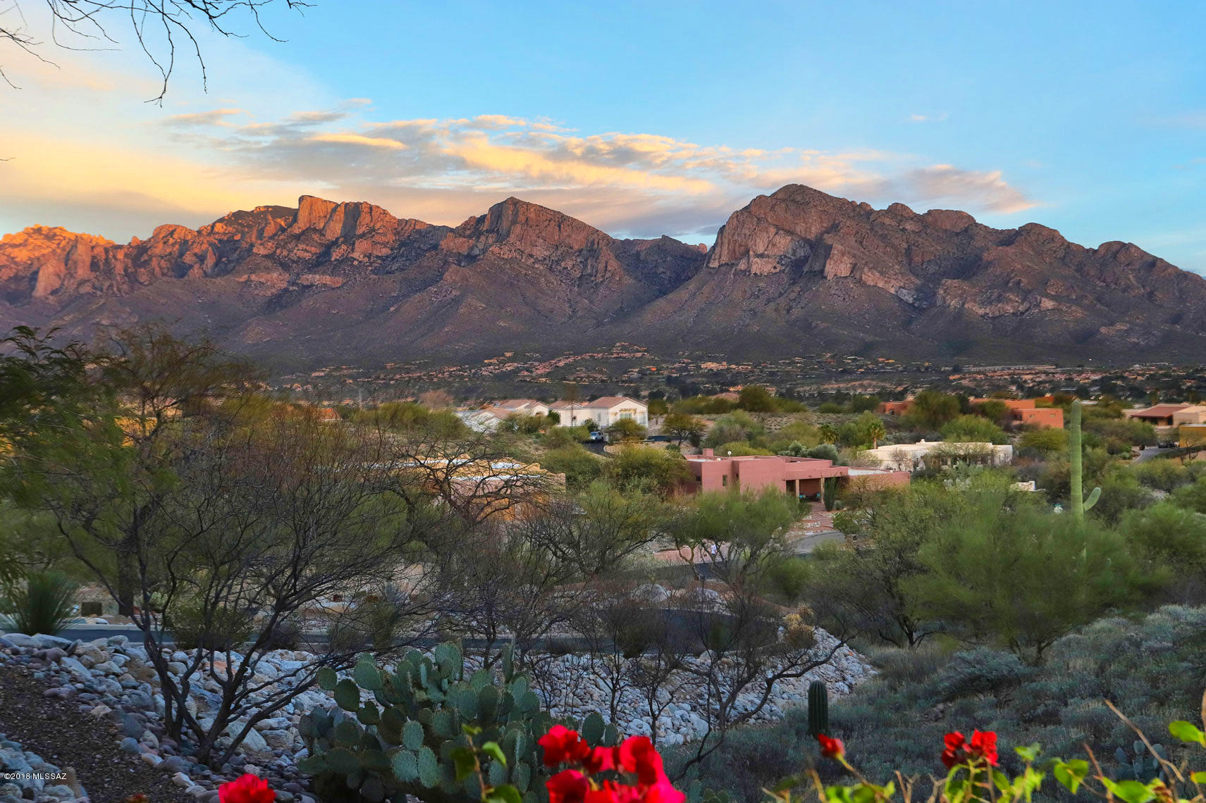 This magnificent hilltop custom move-in ready home is more than a fabulous place to live, it is a lifestyle. Resting peacefully and privately atop a hill and enjoying spectacular sweeping 180* eastern views of the Catalina Mountain range and a 180* panoramic southern/western view of Tucson’s city lights and the Tucson Mountains, both the luxurious home and its location are simply irreplaceable. The entry is up a long softly winding driveway (replaced in 2013 and resurfaced in 2016) to a delightful gated garden courtyard with a soft rosemary fragrance. Inside, enjoy up-close-and-personal views of famed Pusch Ridge from the graciously large salon with its’ lovely hand-painted mural of Tuscany, a favorite of the owners, and the broad brick terrace extending the length of the home. A large open kitchen, great for entertaining family and friends, has countertops of luxuriously gorgeous and unique Brazilian granite, set off by a well-coordinated tile backsplash. High-end appliances include Thermador gas cooktop, bun warmer drawer, microwave convection and regular ovens, a newer GE stainless steel slate finish refrigerator with cafÃ© doors and freezer below and a matching newer GE slate finish dishwasher.  The double stainless steel sink with pullout faucet overlooks the courtyard flowers. A pantry closet provides pullout drawers. A spice roll-out drawer and pull-out carving board are also featured in the kitchen. The kitchen opens to the generously sized dining area, with a new chandelier and built-in buffet also topped with rich Brazilian granite. Off the dining room is a sitting area with a built-in desk and display shelving and cabinets, with views of a lush green desert gully. A guest room off the sitting room has a walk-in closet, an en-suite bath with a door (currently a doggie door but original cherry-wood & glass door is in garage) out to a private brick terrace shaded by a large prolific lemon tree, a doggie run, and a fully fenced and irrigated sunny 10 x 14 vegetable garden. Returning inside, the welcoming salon enjoys a tall cathedral ceiling of wood beams and planks, and a large gas-supplied wood burning fireplace with a striking surround of calcite stone richly colored with iron minerals. (The homeowner is a mineralogist.) A dry bar has more of the gorgeous Brazilian granite as a counter. A piano and harp currently grace the salon, but that space could also be another sitting area. From the salon, with its large windows framing those fabulous Pusch Ridge views, step outside the double glass doors to the brick terrace with a border of bougainvillea. Pour yourself an adult beverage, put on some soft music to play through the high-quality speakers found both inside and outside the home, and enjoy the pink-orange-purple sunsets of the Arizona skies and the sweeping vistas across the Tucson Valley to the Santa RIta and Tucson Mountains as city lights flicker on. Or continue to the elegant freeform pool, with cool decking surround, shade from mature mesquite trees, and another seating area. Brick planters provide another lovely garden spot with morning sun. Back inside, the master bedroom on the south side of the home has similar views, and a handsome wood burning fireplace for chilly evenings. The master bath sports a jacuzzi tub, Carrera Italian marble countertops, a subway-tiled glassed-in oversized shower, large walk-in closet and atrium in addition to views of the Tucson Mountains. On the north end of the home is a den with gorgeous wood plank floors, more fabulous views, and a cozy window seat; this can be converted to a bedroom by putting up the beautiful original cherry-wood  (stored in garage) and putting back a closet that was removed and enlarged for the owner's mineral collection.  An oversized laundry room has more of those gorgeous Brazilian granite counters, a home office space with mail cubbies, storage cabinets, and a drying area. The oversized & extended 3 car garage (on the backside of the home so not visible when one arrives at the home) is quite amazing, with a workshop space enjoying fabulous views, room for tons of storage and an air-conditioned/heated "man cave" perfect for an office, author's writing space or craft room.  Most of the public areas are floored in gleaming Italian tile (grout recently cleaned and tiles polished).  The home is light and bright with double pane tinted windows and skylights throughout. It has been incredibly well  maintained: new hot water heater in 2014, septic tank cleaned 2014, new pool pump and motor seal kit 2014, pool creepy crawler replaced 2017, new irrigation system 2016, chimneys cleaned 2016, interior painted including garage 2016, tile roof redone 2014 with warranty through 2019, new garbage disposal 2017, flat roof resurfaced 2015 (and checked twice yearly), furnace and air conditioning units replace 2009, new furnace south side of home 2018, all lighting is LED as of 2017....meticulous owners! Fabulous area, of course...terrific shopping, entertainment, dining, and medical facilities are nearby as is hiking and biking (ask about the recently completed 170 mile Tucson Loop that can be accessed just moments away.) You are invited to make an appointment to see this delightful slice of Paradise as soon as convenient.
