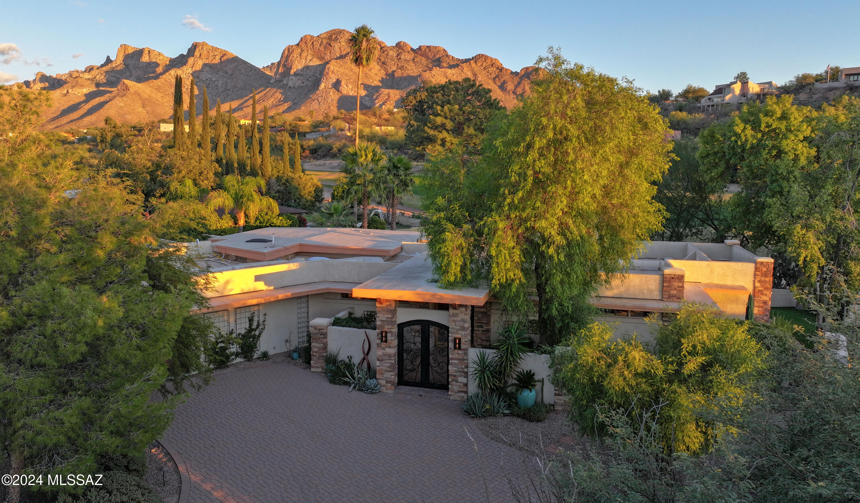 Nestled within the prestigious Oro Valley Country Club, this stunning 3-bedroom, 3.5-bath custom residence perfectly blends sophistication and comfort. Designed with the discerning homeowner in mind, the grand foyer adorned with striking ledger rock accents, sets the tone for the rest of the home. The spacious Great Room boasts a wood-beamed ceiling, a conversation area with gas fireplace, makes it the ideal space for entertaining guests in style. The Chef's dream kitchen features custom knotty alder cabinetry, granite countertops, a farm sink, and a suite of premium stainless-steel appliances including a warming drawer, expansive island and a coffee bar. The pièce de résistance is the climate-controlled, 540 bottled wine room—a perfect spot to store your finest vintages.  con't. Custom built-in desk and cabinets meets your home office needs. The versatile media/game room is a showstopper, featuring a wet walk-around bar, a 10-foot projection TV, and surround sound. Whether it's movie nights or lively gatherings, this space is sure to impress.  Step outside to a beautifully landscaped backyard that adjoins the OVCC Hole #12 fairway.  The outdoor kitchen equipped with gas grill, refrigerator, and sink makes al fresco dining a breeze. Unwind in the private hot tub while soaking in the captivating views of Pusch Ridge. The primary suite also includes a secluded patio with a fireplace, dual ceiling fans, and skylights for year-round enjoyment.  Escape to the luxurious primary suite, complete with French doors that open to breathtaking backyard and Catalina Mountain views. Enjoy the retreat with gas fireplace, dual custom closets with organizers, and a spa-inspired bathroom with a jetted tub, split vanities, and intricate custom tile work. Each Guest bedroom offers unique comforts. One features a private ensuite with a porcelain copper vanity, while the other boasts a private patio and a nearby bathroom with a waterfall tile shower and glass vessel sink. A remodeled powder room with a sleek modern vessel. Additional amenities include an oversized 2-car garage with a mini-split system and separate garage door for golf cart area.  A single car garage with workshop & sink. With 3 HVAC systems and 9 skylights, this home is as energy efficient as it is luxurious. This exquisite property combines luxury, convenience, and thoughtful design, creating the ultimate living experience.