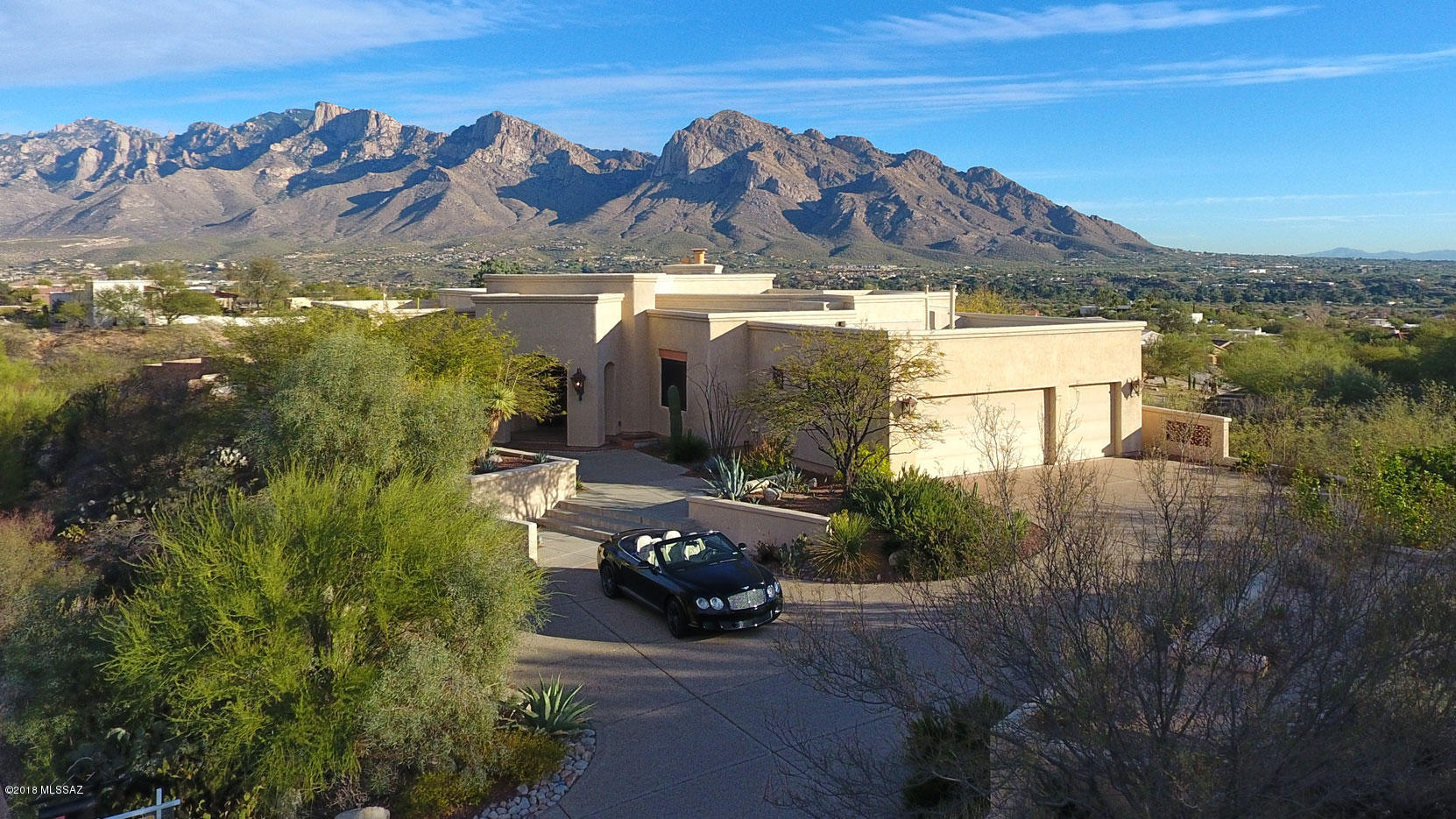 A lovely and meticulously built custom home with Southwestern architectural elements and highest quality construction, thoughtfully planned and executed, with panoramic views of the Catalina Mountains and famed Pusch Ridge, is now available for the first time. This gem is located in exclusive gated Canada Hills Estates in Oro Valley. The home is warm, inviting and attractive, with some of the best possible views of the Catalina Mountains from nearly every window. It’s a spectacular spot to enjoy sunrises, sunsets and the monsoons coming over the mountains, as well as city lights and views across the Tucson Valley from the Catalina Mountains to the Santa Rita Mountains, from inside through multiple large windows and glass sliding doors, or out on the elegant covered terraces surrounded by mature landscaping. The home is situated on a large lot with no immediate neighbors, providing outstanding privacy. It's light and bright with natural light and high ceilings, and has a comfortable feeling while maintaining a sense of elegance. Enter though the custom large front door into a long gallery entry hall that provides your first views of the gorgeous views across the living area, on either side of the warmly designed gas fireplace with its' hearth of Saltillo tiles and carved wooden mantel above. Enjoy the richly beamed ceilings of Vegas with carved decorative Southwestern style corbels.  The flooring is rich Saltillo tile, accented with handsome Talavera tiles, throughout the home except for carpeted bedroom and travertine baths. Rooms are well-sized for intimate moments or equally for casual entertaining. The dining and living areas look directly at Pusch Ridge and the entire Catalina Mountain Range as seen from their west side, all the way up to Mt. Lemmon. The dining area is accented with a fabulous one-of-a-kind chandelier designed by the owners and has more beams with carved corbels. An open and inviting kitchen enjoys richly shaded green granite countertops, Talavera tile backsplashes, a small desk area and plenty of golden shaded alder cabinets including a pantry. Appliances are all stainless and include Dacor cooktop, warming drawer, wall oven and microwave, Bosch dishwasher, Refrigerator with French cafÃ© doors, Kitchen Aid Instant Hot Water feature and a newer Grohe faucet. A custom and very charming plaster "beehive" over the cooktop provides a hood element for the kitchen. The hallways have attractive and nicely lit art niches. The spacious master bedroom opens through glass sliding doors to its' own terrace, with lovely mature landscaping and stunning views beyond. A double coffered architectural element accents the ceiling of the bedroom. There is a glass-shelved bookcase built into another niche. The bath area includes walk-in closet and two additional storage closets. Two separate sink areas have travertine counters with lovely custom framing around the sinks. Unique gleaming chrome bath faucets are Italian and were hand-carried by the owners from Europe. A luxuriously large soaking tub is set in a stunning travertine pedestal, there is a glass walled walk-in shower, and the bath area enjoys more stunning "up close and personal" views of Pusch Ridge. A powder room with a delightfully colorful hand-painted sink is nearby, as is a large laundry room with a sink and plenty of space for crafts and/or an office. On the other side of the home is a guest bedroom, and a guest bath with another travertine surrounded sink, accented with Talavera tiles, travertine floors and more richly shaded cabinets. An additional room can be a den/bedroom as needed. A 2 Â½ car garage includes a large storage area. A furniture package may be available. Please see the video attached to this listing. This impeccably-maintained home is now available for viewing by discerning potential occupants at your convenience.