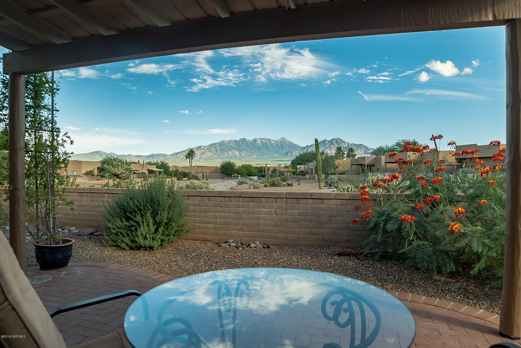 Gorgeous views are an understatement! You will never get tired of the ever changing colors dancing around the Santa Rita Mountain from your back patio at sunset. A Santa Fe Style home with stepped parapet roof lines and decorative vega style downspouts are complimented by carefully manicured desert greenery to create a picture perfect southwest setting. Enter into a cheerful foyer drenched in natural light from an overhead skylight. Easy care tile floors throughout the home help for easy furniture placement and gives spatial dimensions for an open and airy feel. The great room with its centerpiece fireplace adorned with numerous art and media niches creates a wonderful gathering place for your friends and family. And, you can remain part of the festivities while fixing a meal in  this efficient kitchen featuring a serving bar adjacent to the open dining area and separate beverage bar. Space is what this home is all about and you'll love the extra room in the side yard and open natural desert area behind your patio wall. Relax and enjoy the beautiful views and the peaceful lifestyle!
