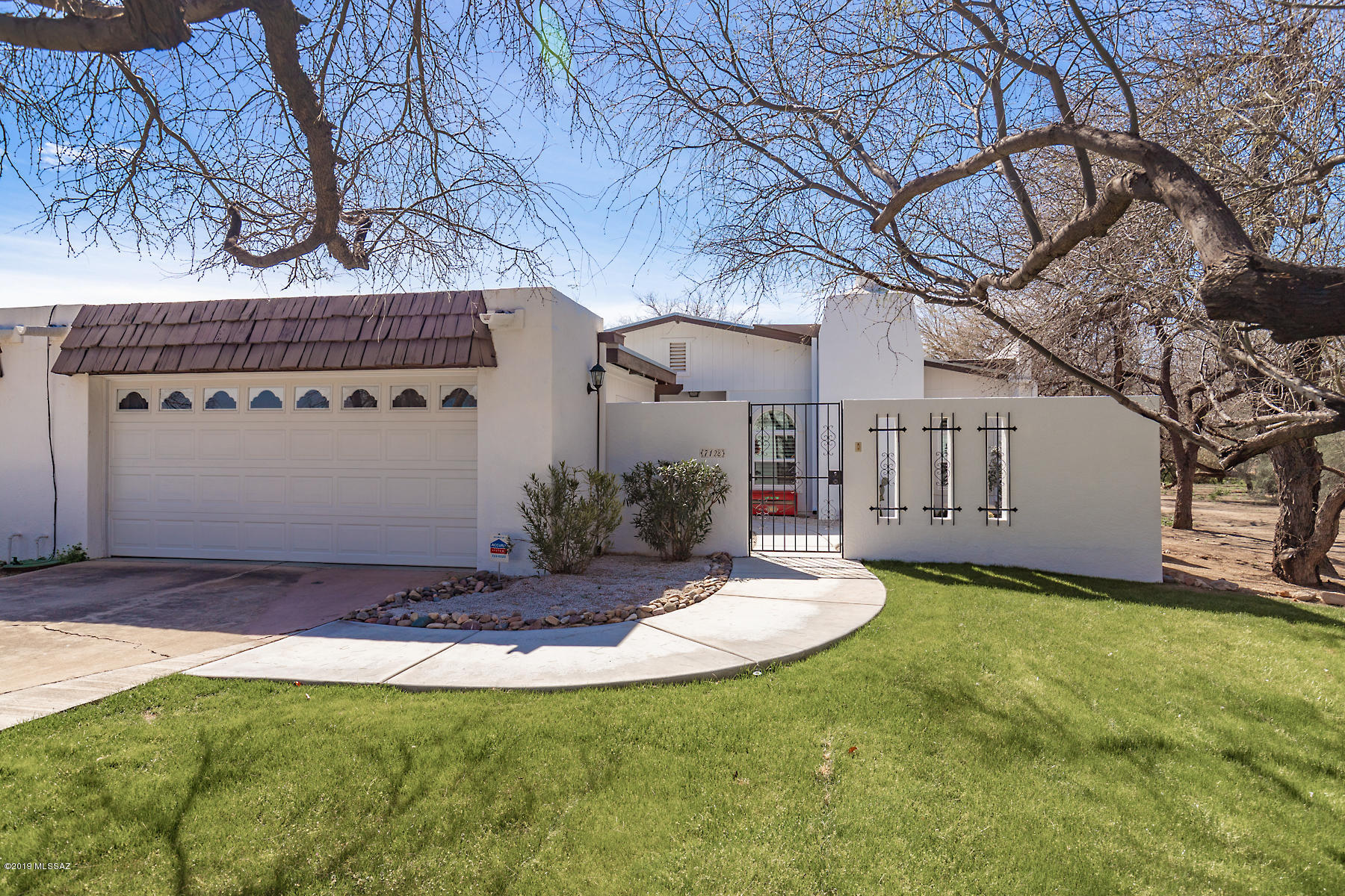 Charming end unit TH, easy living 2 Bed/2 Bath + Den floor plan, lightly lived-in & move-in ready.  Gated courtyard entry, 2-car detached garage has built-in cab's & separate storage rm. Welcoming gas Fplc in the Living Rm. Dining Rm, Lg kitchen area w/ 10' long eating bar & handsome built-in wall-to-wall cabinets w/desk area.  Granite counters in kitchen, tile floors except bedrms, tiled master & 2nd bathrm showers. Louvered shutters, skylights have shades. Split bedrm plan.  Patio door w/dark-out shades from the master to covered patio. All kitchen applc's & W-dryer incl. Built-in vac sys!  Front & rear irrig on drip sys. Pomm, Lemon tree & water feature in the apprx 40'x20' patio area.  Transferable roof warranty to 2/2021. Trail nearby to footpath that runs along the wash. Generous guest parking & mailboxes are just across the entrance to the extra-long driveway, near the foot path to the community pool & tennis courts.