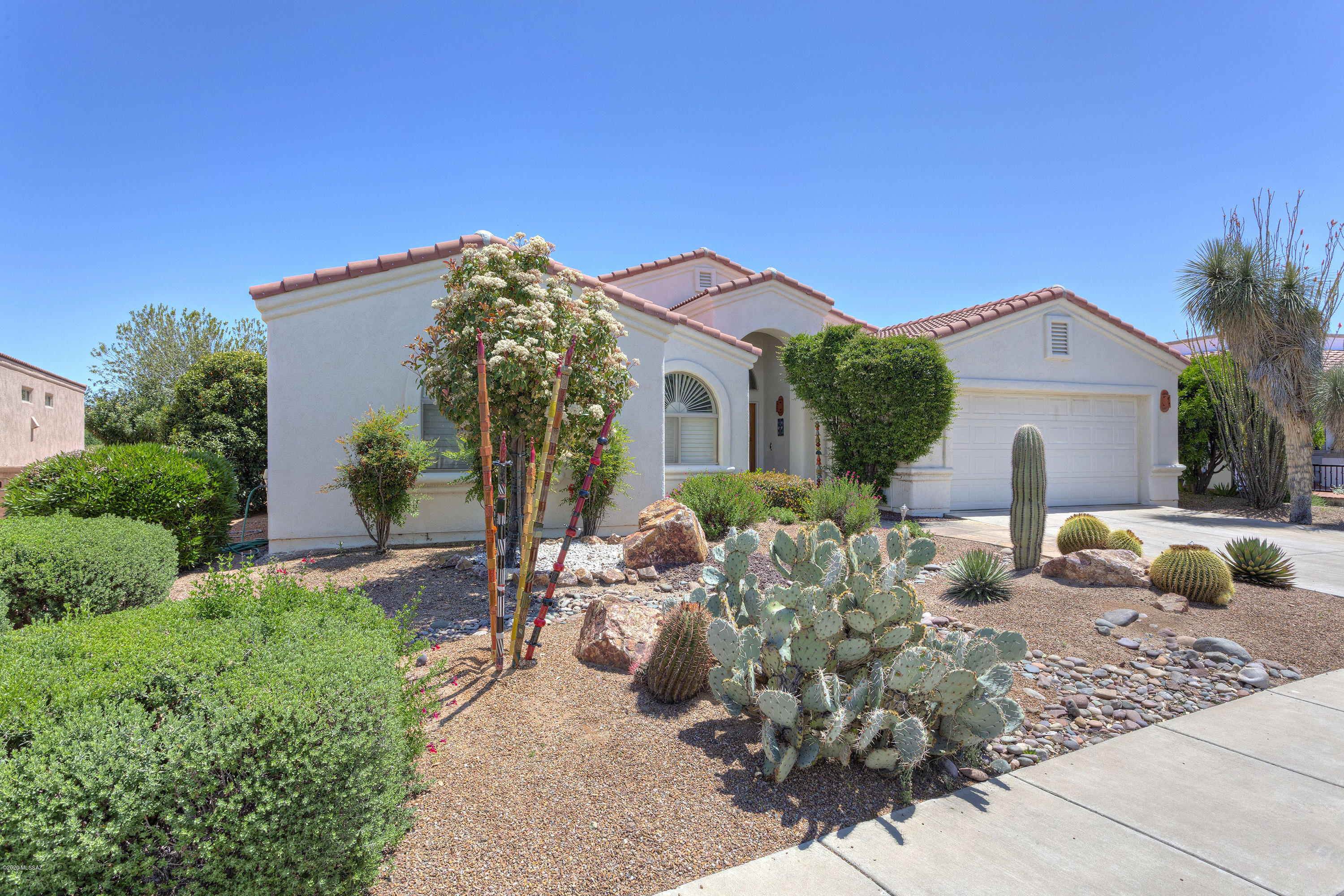 You'll know this house was lovingly cared for as you drive up and see the professional, mature landscaping with beautiful desert plantings. The double alder doors invite you into a grand Great Room with a stunning view of the garden-like backyard with flowering plants and trees, sparkling water feature and mountains. Inside this Riviera floor plan, the vaulted ceilings give the Great Room an expansive feel with f/p, a separate dining area and large open kitchen. The kitchen features a center island with bar stools and a kitchen nook perfect for casual dining. You'll notice the custom window treatments, fine furniture and all furnishings that are being sold with the house. Off the Great Room is the den behind double doors with  custom shutters. There is a huge master suite with bay window that brings the outdoors in and captures the view. Plus, a door that takes you to the covered patio and backyard. The master bath features a large jetted tub and separate shower, dual vanities and linen closet. The guest room and hall bath are at the end of the hall. Rarely used, this room is highlighted by a vaulted ceiling and arched window with custom plantation shutters. The garage is set up with built-in storage cabinets, a separate full-size refrigerator, water softener, and utility sink. This was only used as a part-time home by these original owners. It can now be your year 'round or home away from home!