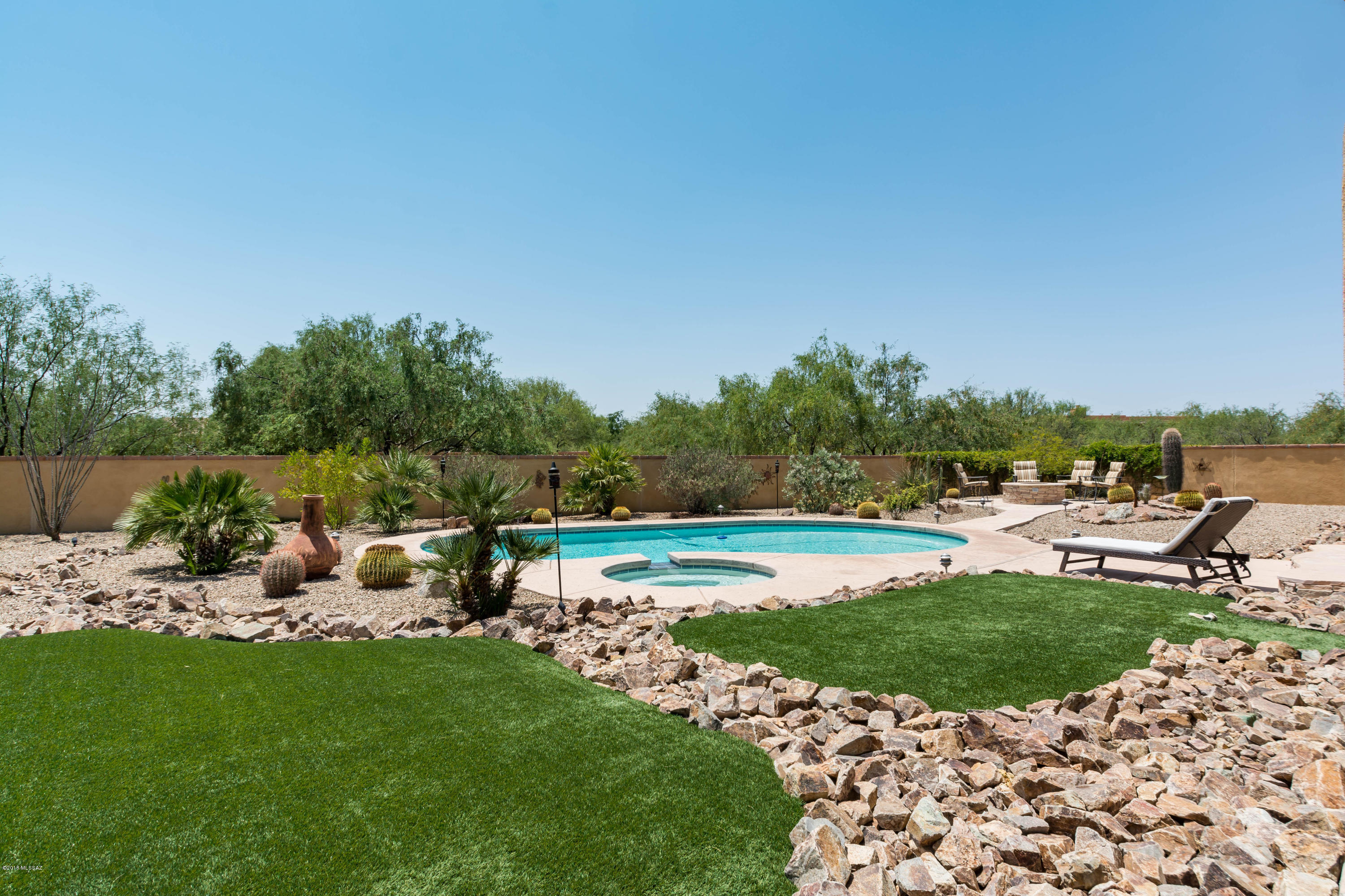 Stunning & spacious Pepper Viner home in a quiet gated, relaxing neighborhood. Vast open floor plan w/many upgraded amenities - a most comfortable home. The flagstone entrance has eye catching 8 ft tall double iron screen doors that allow air flow thru home during comfortable months.The artfuly tiled entry way opens to a large living/formal dining area- perfect for entertaining. The gourmet kitchen is a chef's delight. -beautiful granite counters & sprawling island - great for gatherings. The spacious master suite is located at one end of the home- a private & peaceful retreat. Just as spacious is the master bathroom w/dual vanities, dual walk-in closets & an oversized walk-in shower w/dual shower heads + spacious tub. The 4 additional bedrooms are tiled (1), wood laminate (3) along with 2 additional full baths & 1 half bath. This home has an extended 3 car garage, large ceramic tiled flooring throughout  majority of home, 8 foot doors, upgraded stainless steel appliances, stylish shutters on many windows, a fireplace in the family room, an instant on-demand tankless hot water system, and a large flagstone rear porch w/ceiling fans that look out on to a professionally landscaped backyard with pool, built-in spa and stacked flagstone fire pit. The large backyard is walled w/gates on both sides. The actual lot is almost one acre of land within the gated Tierra Linda subdivision.  This is a gorgeous, private and peaceful home - a grand entertainers home or a grand peaceful retreat.