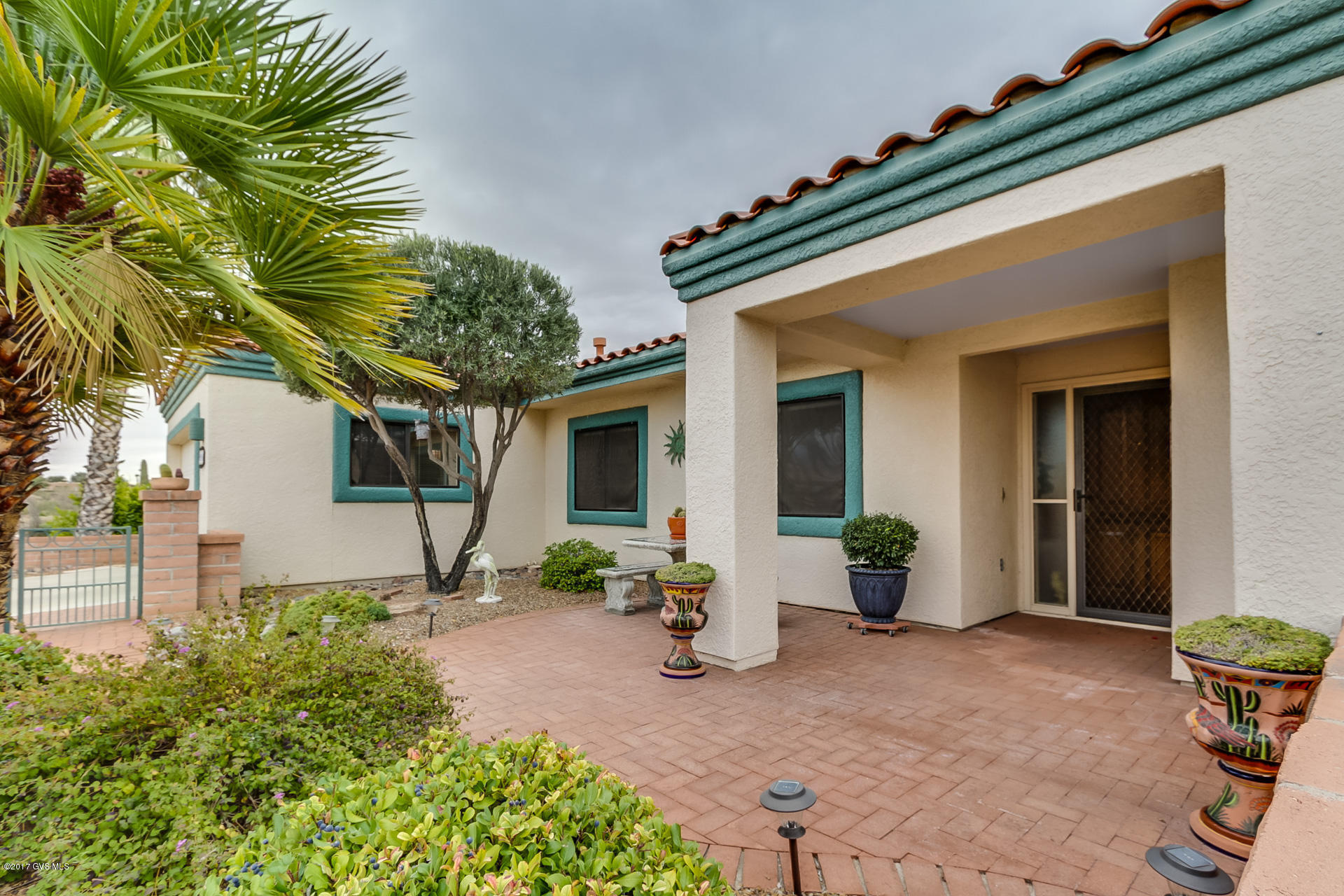A low maintenance front landscaping is crowned by a red brick perimeter wall providing privacy to your front courtyard which offers nice views of the Santa Rita Mountains. Rich wood grain flooring, southwest color tones and a vaulted ceiling hover over this floor plan granting openness and apportionment. The quiet living room has two large opening windows for relaxing and enjoying cool evening breezes while the family room's island media center separates the entertaining area. An efficient U-shaped kitchen design offers abundant workspace, bright white appliances and tile counter tops, a sink with backyard views, an eat-in counter space and easy service to the casual dining area. The desert paint tones continue into your master bedroom suite where you'll find a glass French door access  to the back patio. Plus, the wood flooring follows you into your master bath where double sinks and a spacious walk-in closet deliver convenience and elbow room. A brilliant office space has upgraded modern track lighting making it easy for reading and catching up on your computer work. And, your back patio offers a Santa Fe flare with its huge Ramada covering the red brick pavers giving you a place to relax with friends.
