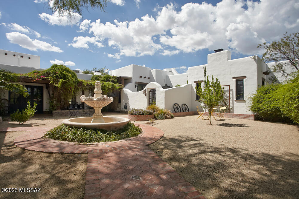 This one will take your breath away! One-of-a-kind 1920's mud adobe in hidden historic enclave in central Tucson, exudes all the ambience of a movie set. Adobe walls encompassing courtyards and lush patios, too many to count. Warm wood floors, beamed ceilings & five fireplaces. Designed by William Penhallow Henderson, a painter, architect and furniture builder from Santa Fe. The mud bricks were all made and baked on the property by a crew of 8 native Puebloans, thus the name Indian House Road. On 1.6 ac property includes 6 bedrooms, 6 baths, owned solar, a private well, a guest house attached to old schoolhouse offers multiple possibilities. Beautiful pool built 2021. Huge yard lined with citrus trees is like your own private park. . See''docs'' for floor plans & list of improvements.