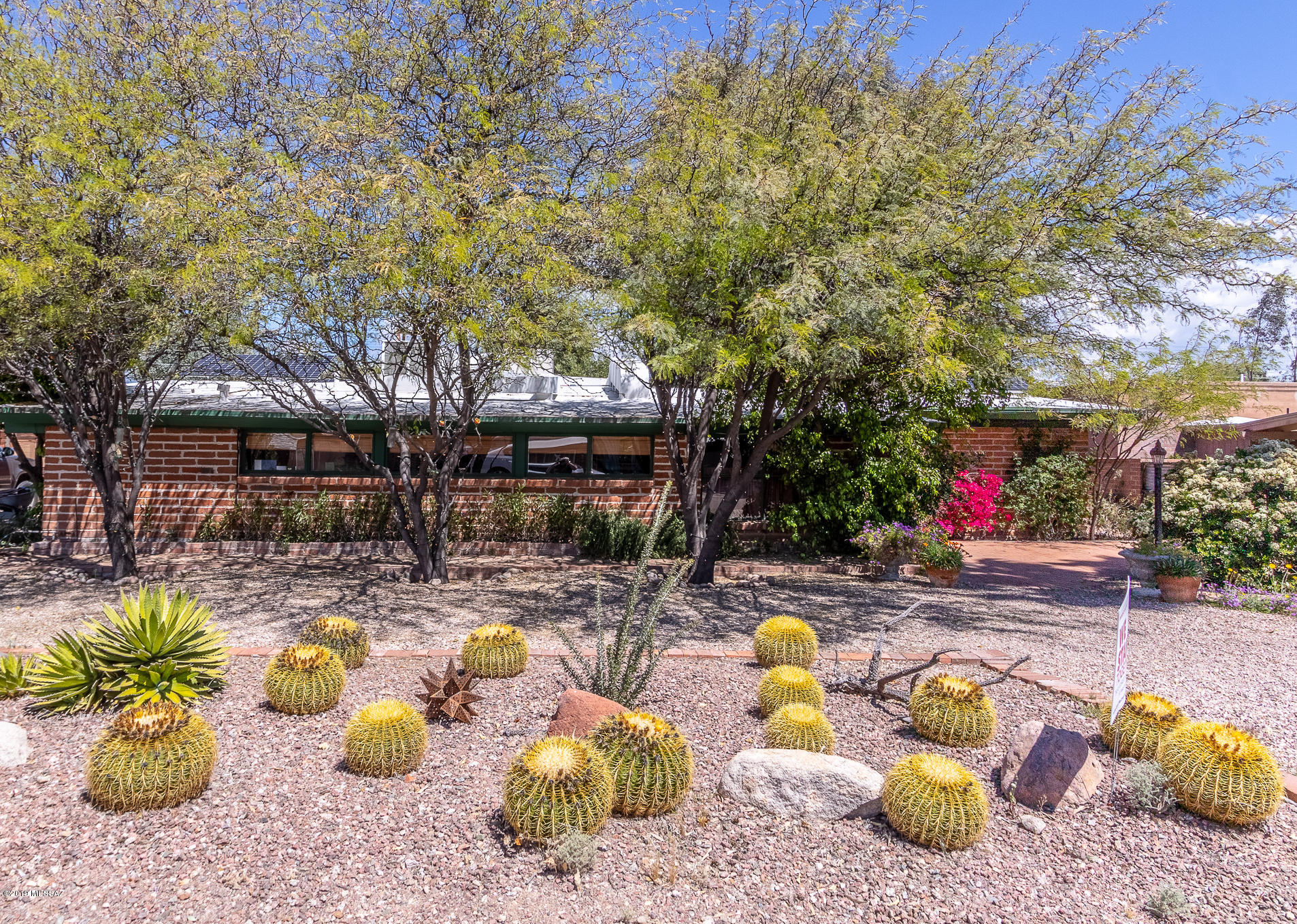 This meticulously cared for, mid-century  home is a Tucson classic. Dual cooling w/ top-tier solar power (10/20 year warranty) = Energy efficiency. Gracious, open living room w/ built-in bookcases, vaulted beam ceiling & 3-sided fireplace.  Formal dining room overlooks brick patio and lush, shaded yard. Chef designed kitchen w/ 6-burner stove, slate counters, copper accents, farm sink, cherry cabinets & near-new s/s Bosch Dishwasher and s/s 2-door fridge.  Breakfast nook & casual family room; Master suite w/ hickory floors, walk-in closets & plant shutters.  Brick patios on all four sides & an always cool shaded driveway. Plenty of storage throughout w/ two large sheds (workshop/potting), surrounded by mature trees & cactus gardens.