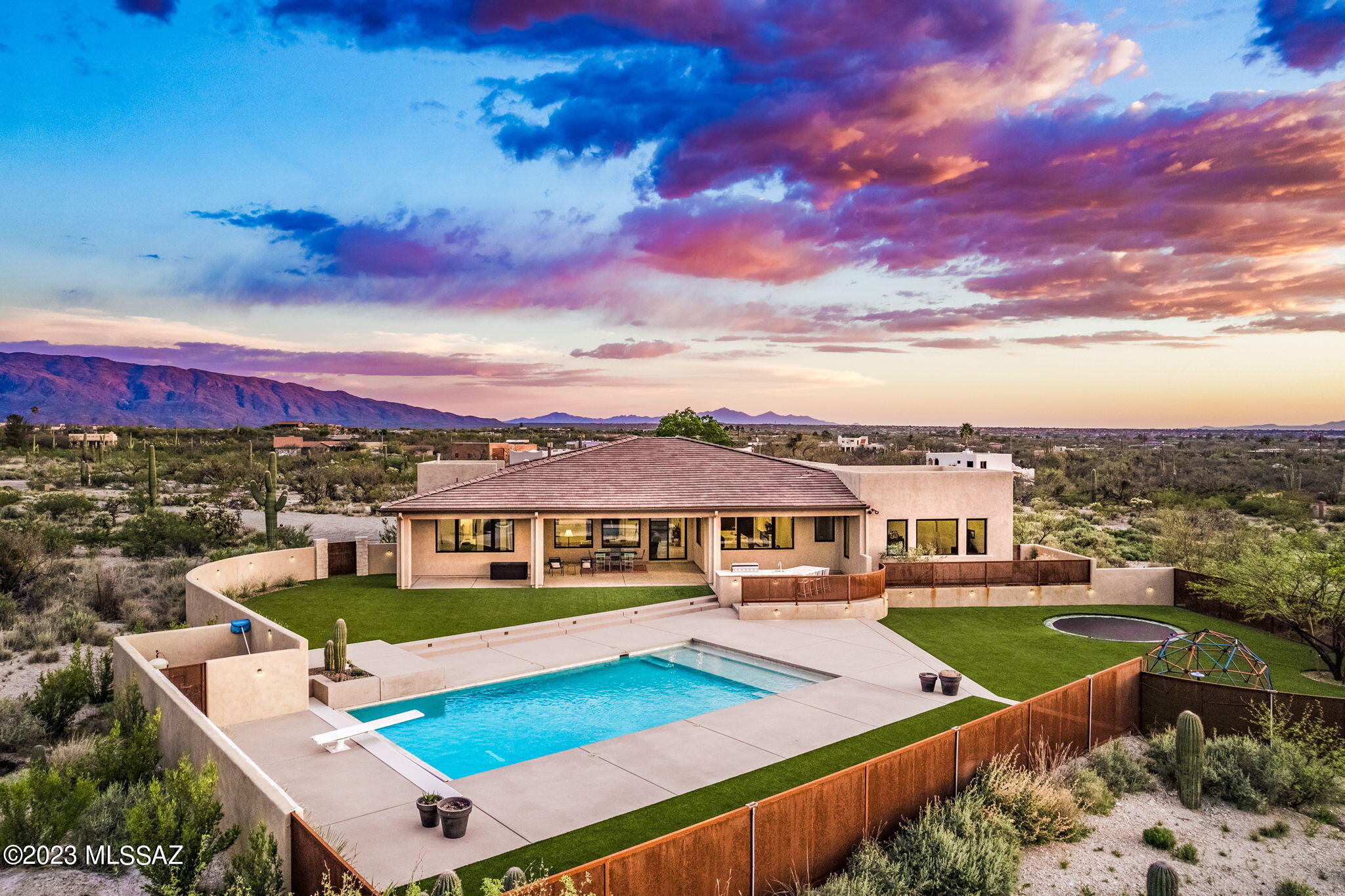 Contemporary oasis set on 2.83 acres with sensational Catalina & Rincon Mountain views perfectly framed by abundant windows in almost every room. Outstanding Great Room Concept is anchored by a DREAM kitchen w/marble waterfall island, paneled Sub-Zero refrigerator, gleaming Wolf range, custom lighting & shaker cabinets; wide-plank engineered wood flooring, Great Room has cozy fp  & views so majestic they serve as art! Primary suite includes luxurious spa-like bath w/dual vanities, walk-in shower & soaking tub; generous guest rms, gorgeous guest baths, a bonus/playroom right off the kitchen perfect for games, movie night, & entertaining. A wow mudroom & backyard that boasts a sparking pool w/automated cover, ez care turf, built-in bbq & bar, in-ground trampoline & deep covered porch. NO HOA