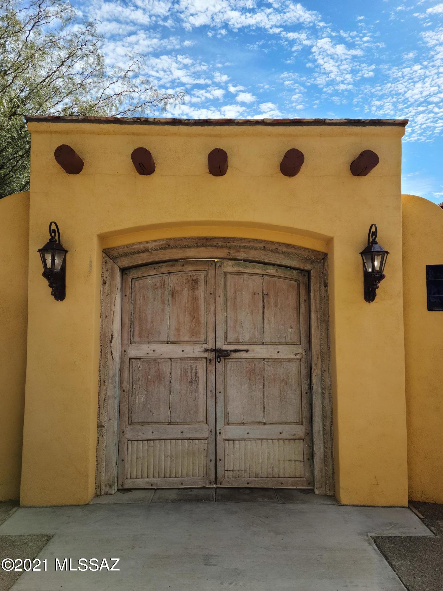 This unique property enjoys unobstructed views of the Santa Rita Mountains, and other spectacular area views. An attractive block fence with adobe trim envelopes the property. With large interior open yard spaces front and back. The property boasts many ''Old World'' built-in touches starting at the front gate circa late 1700's hand made with original forged hardware. The driveway gate and others are hand forged iron by a local ironsmith. The Kitchen door is a Moorish 1700's carving. Also a hand carved cantera hood over the stove. An artisan hard carved a custom cantera fireplace. All 3 bathrooms are beautifully done with custom built-in vanities, tile work and glass. The property has some unfinished areas allowing for a new property steward to create their own oasis in Tubac. A must see