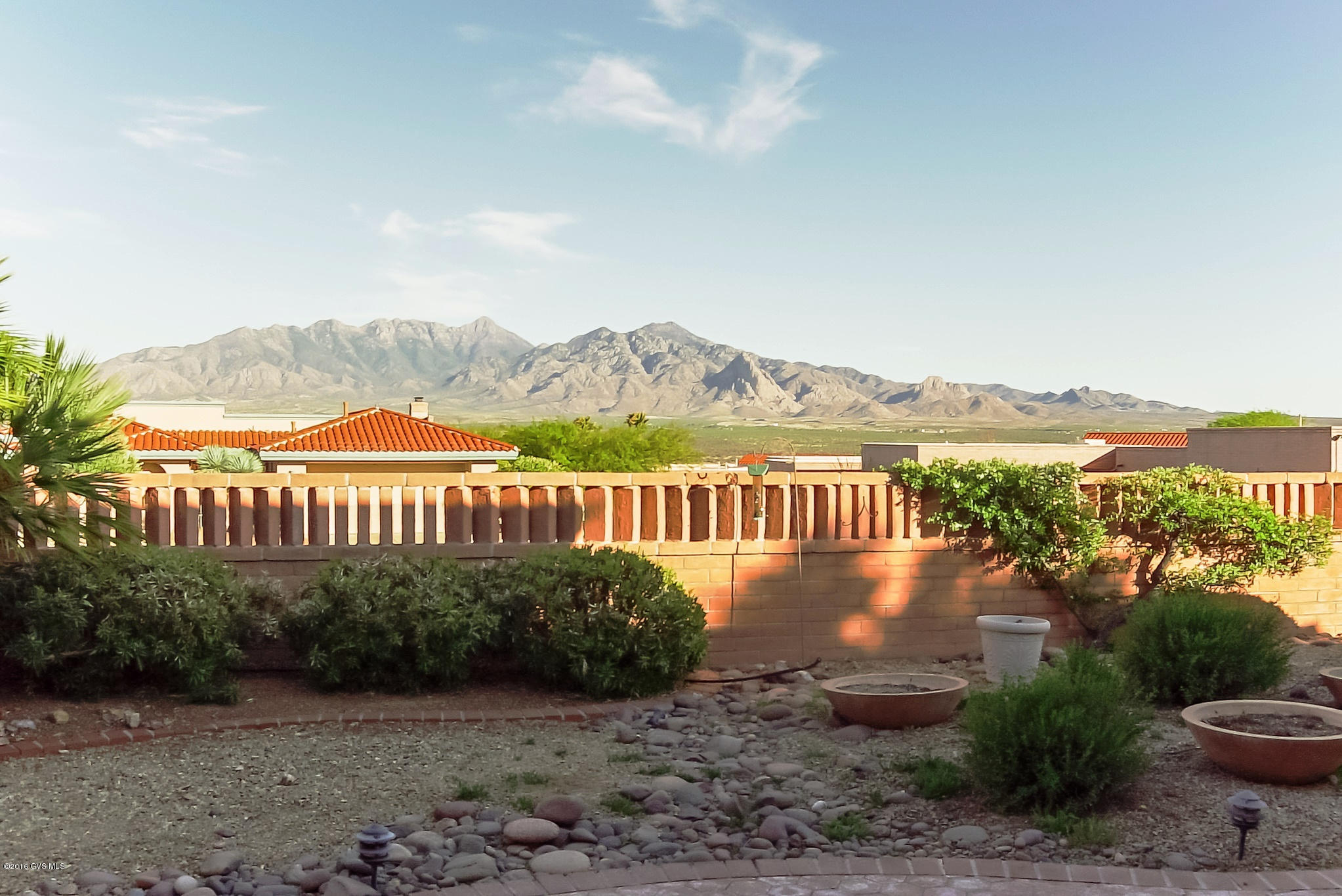 A home offering great curb appeal with Mediterranean roof lines, multi colored rock and desert shrubbery, desert palms and cactus. A wood entry door with 2 side lite panels leads you to a living room featuring a 3-sided fireplace and a wall of windows with stunning views of the Santa Rita Mountains. The heartbeat of this home is a family room with its built-in media center which opens to the kitchen with a prep-cook island encircled by an abundance of white cabinetry. Escape to your peaceful master bedroom and spoil yourself in the luxurious jetted tub centered under two large glass block transom windows. The guest bedroom is also a master suite with private bath. Settle in on your backyard covered patio and relax to the sound of your trickling fountain as you enjoy beautiful  desert landscaping that frames the stunning mountain views!