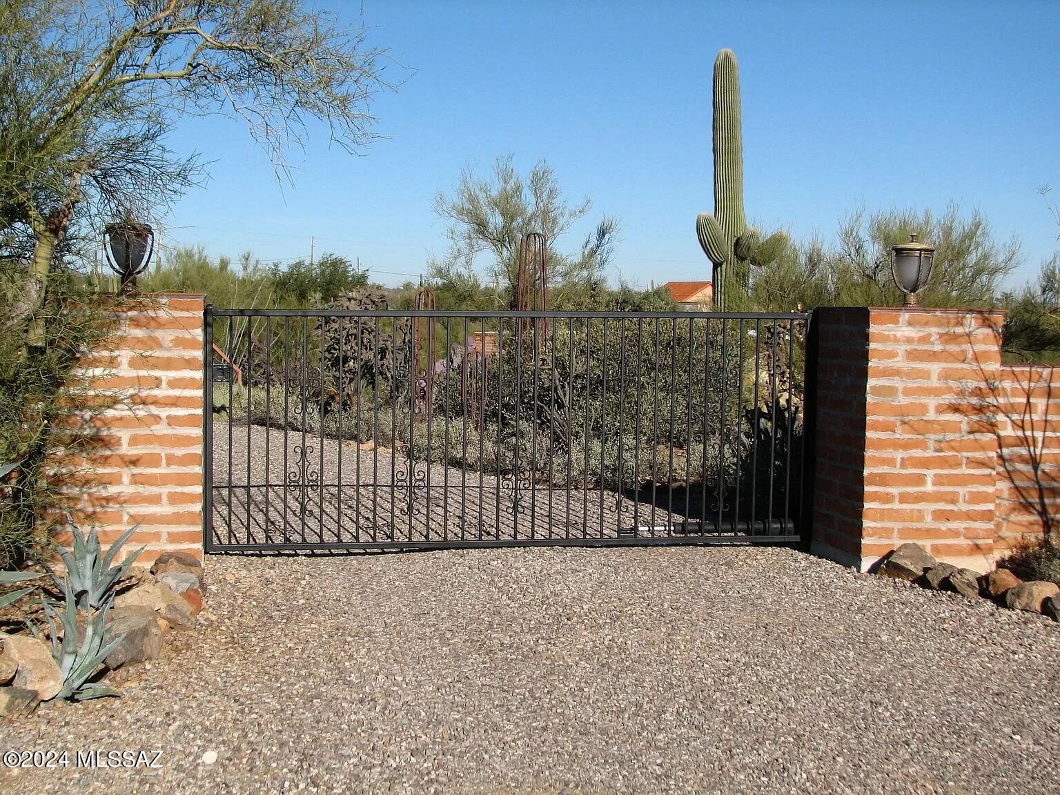 This five-acre jewel is tucked away in the Sonoran Desert and is accessible only through a private gate!  Nestled in your own little sanctuary, but conveniently close to downtown and the I-10.  This serene location combines stunning vistas with a dash of vintage charm. Exhibiting exquisite craftsmanship, this 3,200-square-foot property includes a stunning 1309-square-foot adobe guest house. This home has a mid-century contemporary vibe, with five fireplaces and a floor plan made for numerous family gatherings.  Plenty of outdoor spaces to take advantage of, such as a sizable pool area ideal for swim parties, a magnificent courtyard with stunning sunrise views, and an open covered patio with breathtaking views of the Catalinas.  A new septic system, a replastered pool, & two newer HVACs.