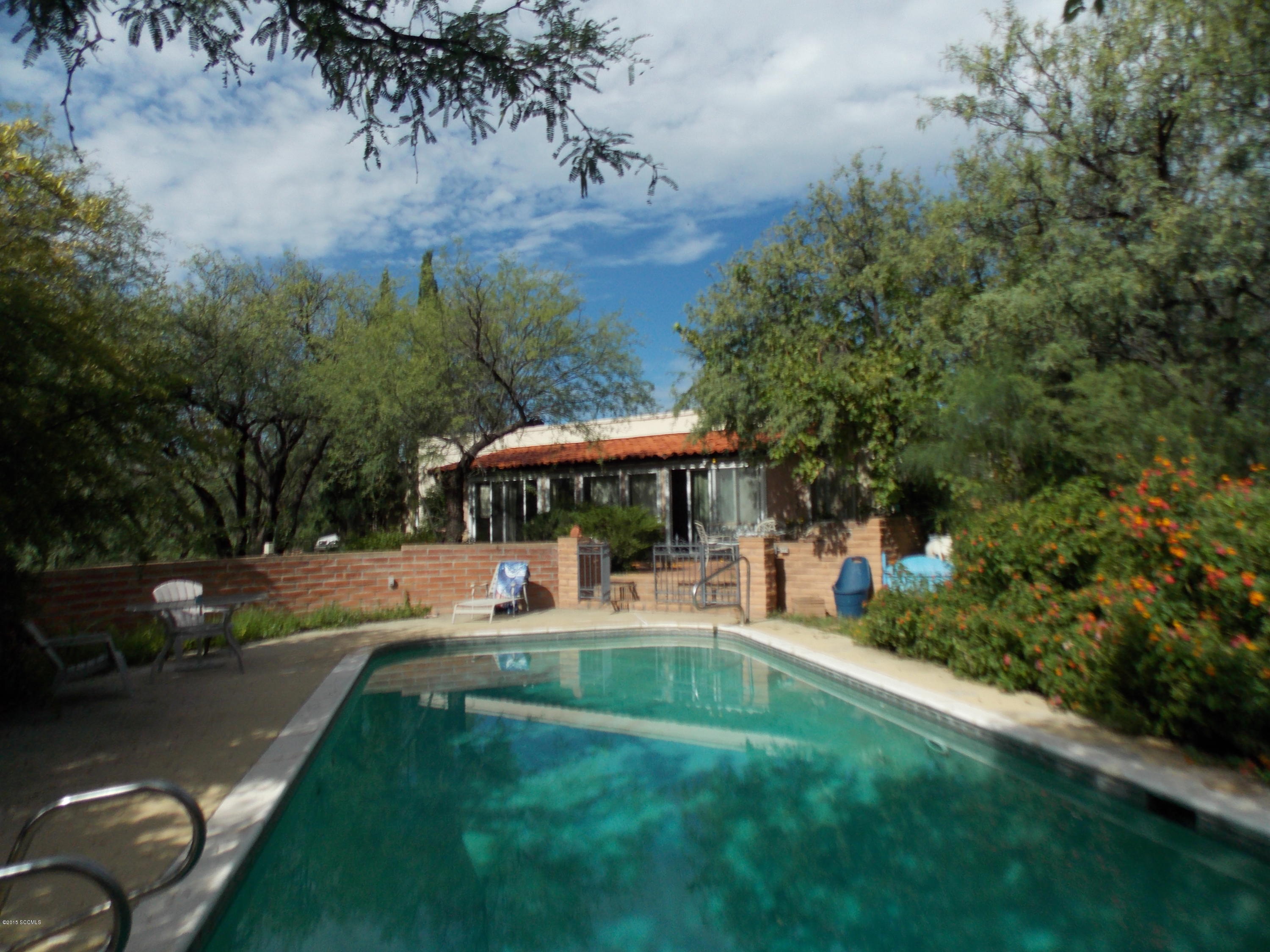 Lovely home with updated kitchen on 1.49 acres surrounded by large mesquites and lush vegetation. Private well, Great indoor spaces-dining area, den, office/studio, enclosed Arizona Room, Great room with fireplace and spacious kitchen, Great outdoor spaces-brick winter patio with fireplace is a welcoming entry, brick summer patio steps down to walled pool, Gazebo under the trees, spacious workshop. This is a gardener's paradise. House sits will back on lot for privacy. Mature vegetation & wate