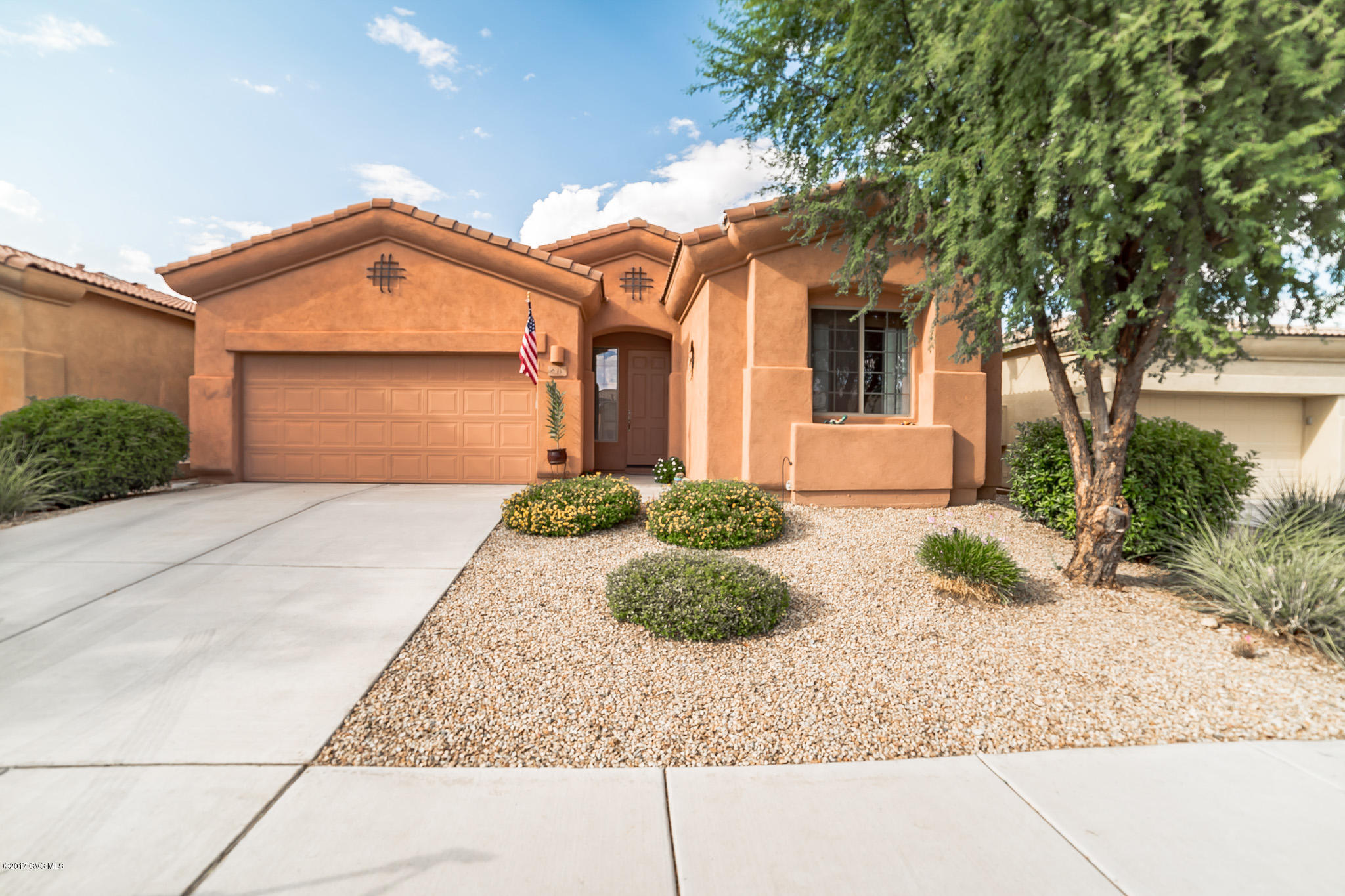 Crown molded cascading roof lines and bump-out architecture creates nice street appeal. You'll enter an open great room with large windows letting in natural light and an angled centerpiece media niche flanking a gas fireplace. This convenient floor plan offers a serving island kitchen with custom pendant lighting, abundant elbow room counter space, double ovens, a gas cooktop and under-cabinet light fixtures. A split bedroom arrangement and double French doors take you into a third bedroom or quiet den Radiant light drenches your master bedroom through twin opening windows and a walk-out patio door. The bath delivers dual sinks and a contemporary curved tub and separate walk in shower. Take some time to sit and relax on your back patio where you'll find a brick paver extension  flowing out to crisp low maintenance desert landscaping surrounded by solid perimeter privacy walls.