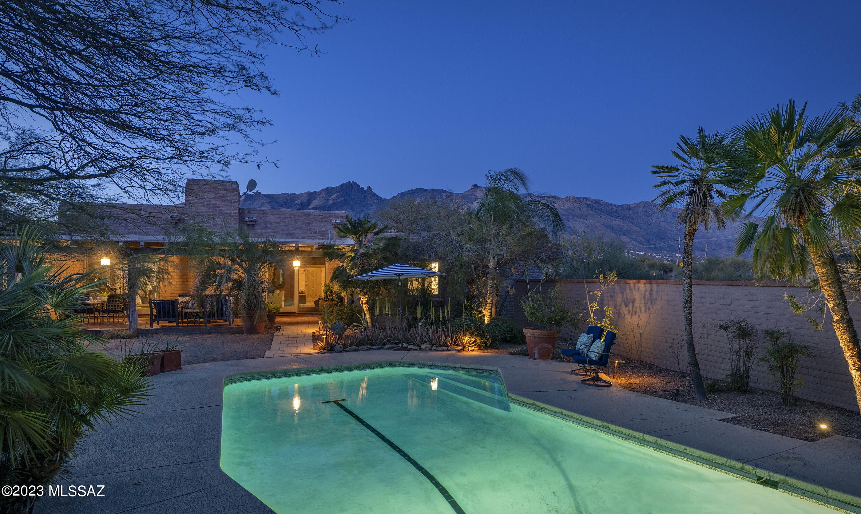A pure expression of regional vernacular juxtaposed against minimalist modern lines, creates the perfect blend of form and function. Built by renowned designer Lewis Hall, this highly in demand design aesthetic stuns with its distinctive amenities and bespoke design elements, offering a level of architecture that is beyond compare. Enter into an understated light-filled and resplendent floor plan that runs north and south along the topography, maximizing the discrete view corridors. Textured walls that accentuate the dimensional massing of space, replete with polished brick paver floors, set against textured and washed burnt adobe vertical walls, providing both a visual and tactile experience. The generous owner's suite is privately sequestered on the east end of the residence featuring oversized dual walk-in dressing closets and luxuriously finished primary bath, which includes a large soaking tub and walk-in shower. The public wing of the residence comprises the living room, dining and kitchen, efficiently showcased in a great room format, creating a warm touchstone of unassuming balance. 

The custom Bulthaup kitchen provides a materially authentic space featuring hand finished forms that harmonize with human ergonomics. Users' movements are carefully choreographed  throughout the space, with the galley experience being strategically situated out of frame, providing a supporting role to all kitchen preparation activities. 

From sunrise to sunset, the interplay of light and shadow shifts, acting in concert with the home, illuminating the complementary materials on display. Voluminous roof lines produce a strong graphic both horizontally and vertically, responding to the external elements, while enhancing the quality and scale of the interior spaces. 

A large covered veranda captures the romance of the desert southwest, running the length of the southern edge of the residence. Sliding glass doors flank the statement fireplace, providing a seamless flow from the interior to the exterior of the great room, creating an extension of the outdoor living floor space. 

Drifts of colorful landscapes highlight the pool that serves as a vibrant counterpoint to the surrounding foliage of the natural desert landscape, creating a nested experience resulting in a beautiful and cohesive environment. This timeless design is thoughtfully executed and combines not only significant spaces for both indoor and outdoor entertaining, but also perfectly scaled private spaces for comfortable everyday living.