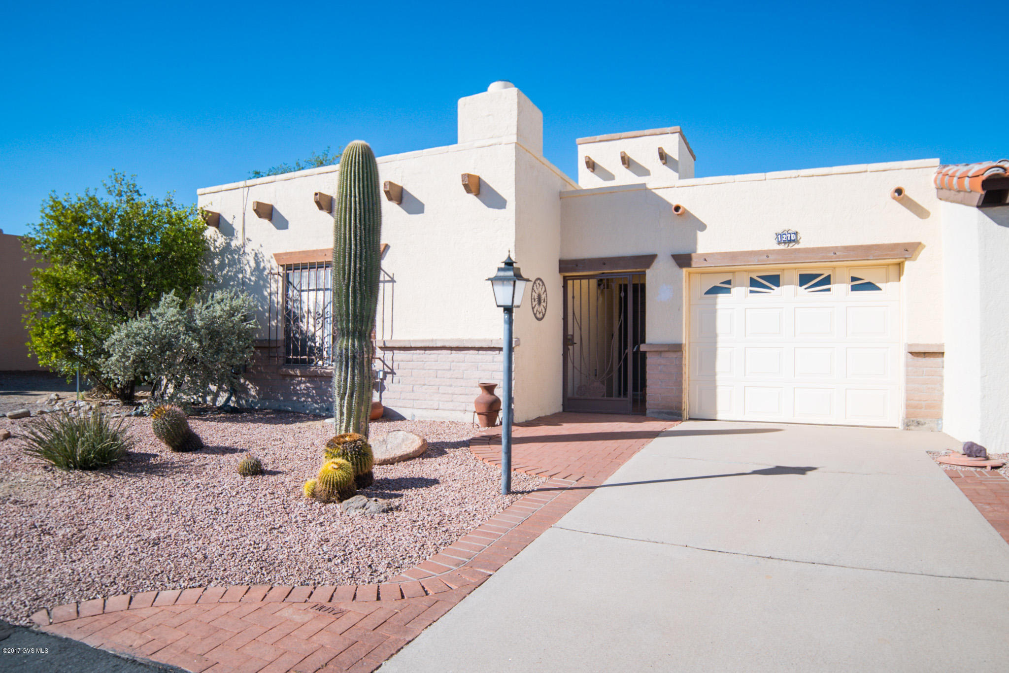 Pride of ownership shows in this upgraded and well cared for home. You're greeted by crisp desert landscaping featuring an old Saguaro cactus, red brick walkway extensions, decorative brick and stylish Spanish Vega beams. Blanketed in oversized floor tile, the living room displays a centerpiece southwest corner Kiva fireplace, wood plantation shutters, custom paint colors and an open dining area. The kitchen is sheathed in granite counter tops with an under-counter single basin sink and a quick clean glass cooktop range under the radiance of a large skylight. The tile flooring, granite counter tops and soft tone paint colors continue into your master bedroom which features a built-in makeup station and 3 pullout drawers, an upgraded vanity with a hammered copper basin and a custom  mirror with embedded turquoise nuggets. Stay free from the elements in your fully tiled and enclosed Arizona room delivering additional living space to recline within the natural desert backyard setting. Or, step out to your back patio with brick pavers flowing out to river rock gardens and swaying mature desert palm trees.