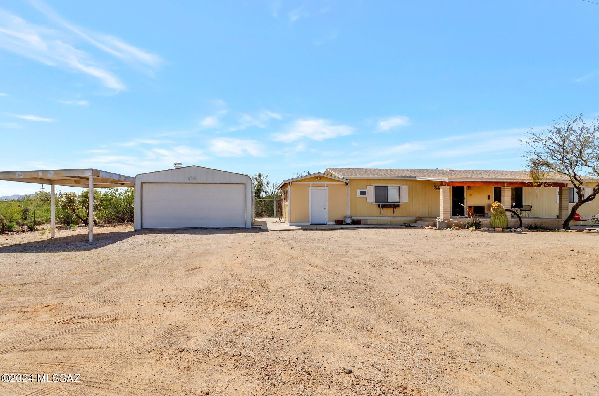 This completely fenced 1.01 acre property on a paved road has a circular drive, gated on each end.  Enter the home via the concrete walkway and steps to the nice front porch with wonderful mountain views.  The interior is freshly painted and has laminate flooring throughout. An enclosed storage room/area is attached to the home.  In addition, the property has a 20 x 20 detached garage/workshop with attached carport, a small storage shed, and a chain-link fenced dog enclosure.  The new roof (2023) has a 5-year warranty that is transferable. 
Access to the Tucson Mountain Park is across  street for hiking, horseback riding, and mountain biking.