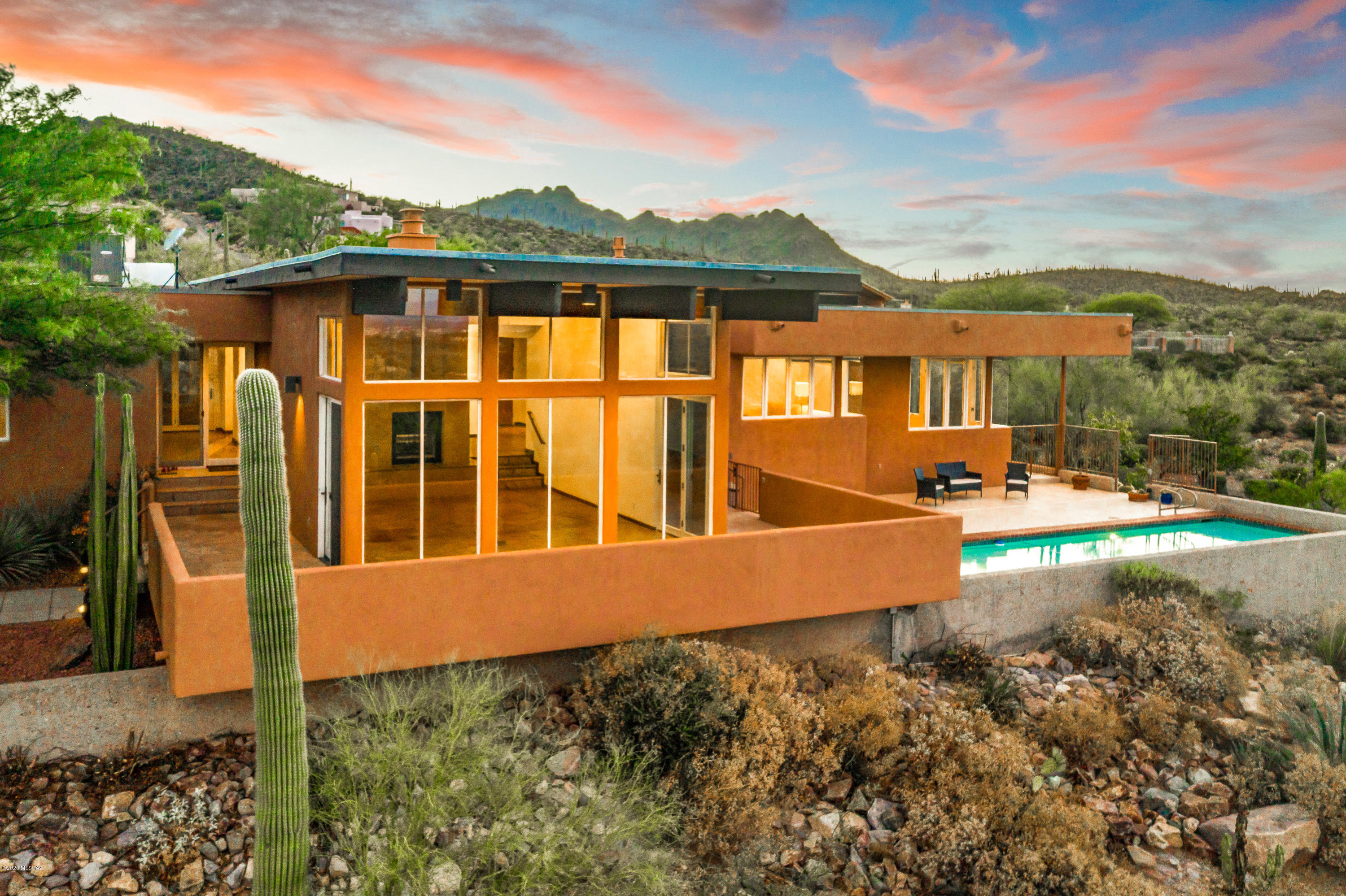 Nestled in the Tucson Mountain Foothills, with sweeping views of our beloved mountain ranges and city lights, a unique and exquisite masterpiece awaits! A generous 3300sq ft, 3Bed/4Bath, 2 car gar. w/workshop space & pool gem features a blend of organic and modern touches to create a one of a kind grand abode. Artistry & symmetry are present in every corner. The architect/owners designed this as their dream home. The Southwest prairie design is inspired by the architectural style of world-renowned Frank Lloyd Wright, whom owner studied under, to blend organically into the rugged desertscape and surrounding mountains. Open floor plan & floor-to-ceiling windows bring the vibrant desert scenery inside creating a seamless transition. Overhanging eaves caress the surrounding porches with shade, without the use of columns, providing a delightful respite enabling you to savor the magnificent valley. Large beams of Glulam wood and tongue & groove wood ceiling running the length of the main structure along with flagstone floors incorporate nature's finest elements into a southwestern flavored masterpiece. Enjoy fantastic gatherings while dining beside the double-sided fireplace and have ease of movement to the Living room which offers million dollar views and multiple outdoor access points. Morning sunrises stream in while, at night, the city twinkles below. Host unforgettable gatherings or enjoy family time out on your pool deck and freshly re-plastered lap pool! Million dollar views will be the envy of all!
Multiple Bedroom en suites provide flexibility, comfort, privacy and spacious luxury for extended/multi generational families. The Owner's suite also has a magnificent extra space with fireplace to be used as you please- home office perfect for current times, seating or exercise area. The 2nd Bedroom has private access door to front walkway. Perfect guest quarters. The 3rd bedroom has a flexplan. Having a sink, counter space and mini fridge, it offers a fantastic, large and private space for in-laws. Can be used as a media room as well. A plethora of private porches surround your home. The flexible floorplan enables you to live the way you want to!
Chef's kitchen with a serene desert view, granite counters, convection ovens, down draft vent on gas cooktop, pull-out drawers,  bar seating and casual dining area are sure to please! Open the door to your left side porch and enjoy the soothing sounds of the pond's waterfall! Hop across the steppingstones onto stairs that lead to your private trail which interconnects outdoor living spaces! The porch to the right of kitchen w/doggie door lead you to the enclosed dog run! Unison is the key word in your new home. A decorative eyebrow graces the 2 car garage.  Exterior skylights in bedroom patio areas create peaks of sky while enjoying the shade while interior solar tubes bring bright sunlight into central areas. Casement windows improve fresh air flow through the house. 
Lovingly tended outdoor spaces, pool, pond and gardens ensure natural shade and numerous options for maximum enjoyment. Multiple fruit trees on auto timer systems line your own walking path complete with whimsical steps. A true Zen home just 2 minutes from Gates Pass, less than 10 from I-10 and convenient access to shopping, hospital, Downtown, UofA, DMAFB, Caterpillar, Raytheon and amazing hiking/biking! No HOA. This is home! Matterport tour allows you to "walk" the home. Floorplan under docs tab. Come see it and Bring Your Offer!