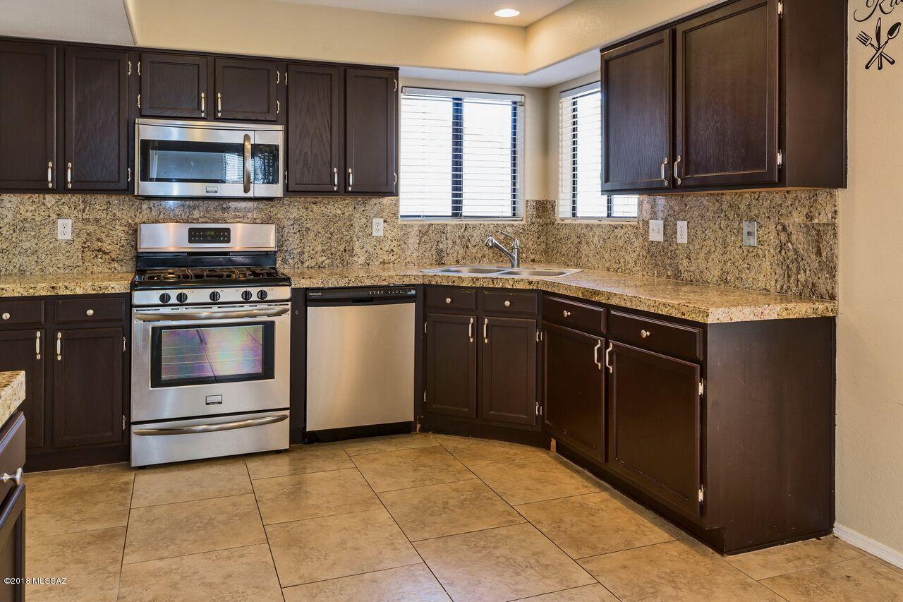 This beautifully upgraded 3 bedroom/2.5 bath home is waiting for you! Kitchen boasts granite counters and stainless appliances including gas stove. Master and guest bedrooms have views of the mountains. En-suite features dual vanities, granite counters, tiled shower, garden tub and large walk in closet. 18'' ceramic tile throughout downstairs. Garage includes epoxy coating and built in cabinets. Entertain friends and family in your beautiful backyard with built in fire pit, flagstone covered patio and satellite patio! Located in Northwest Tucson across from The Omni Tucson National Resort and Golf Course.