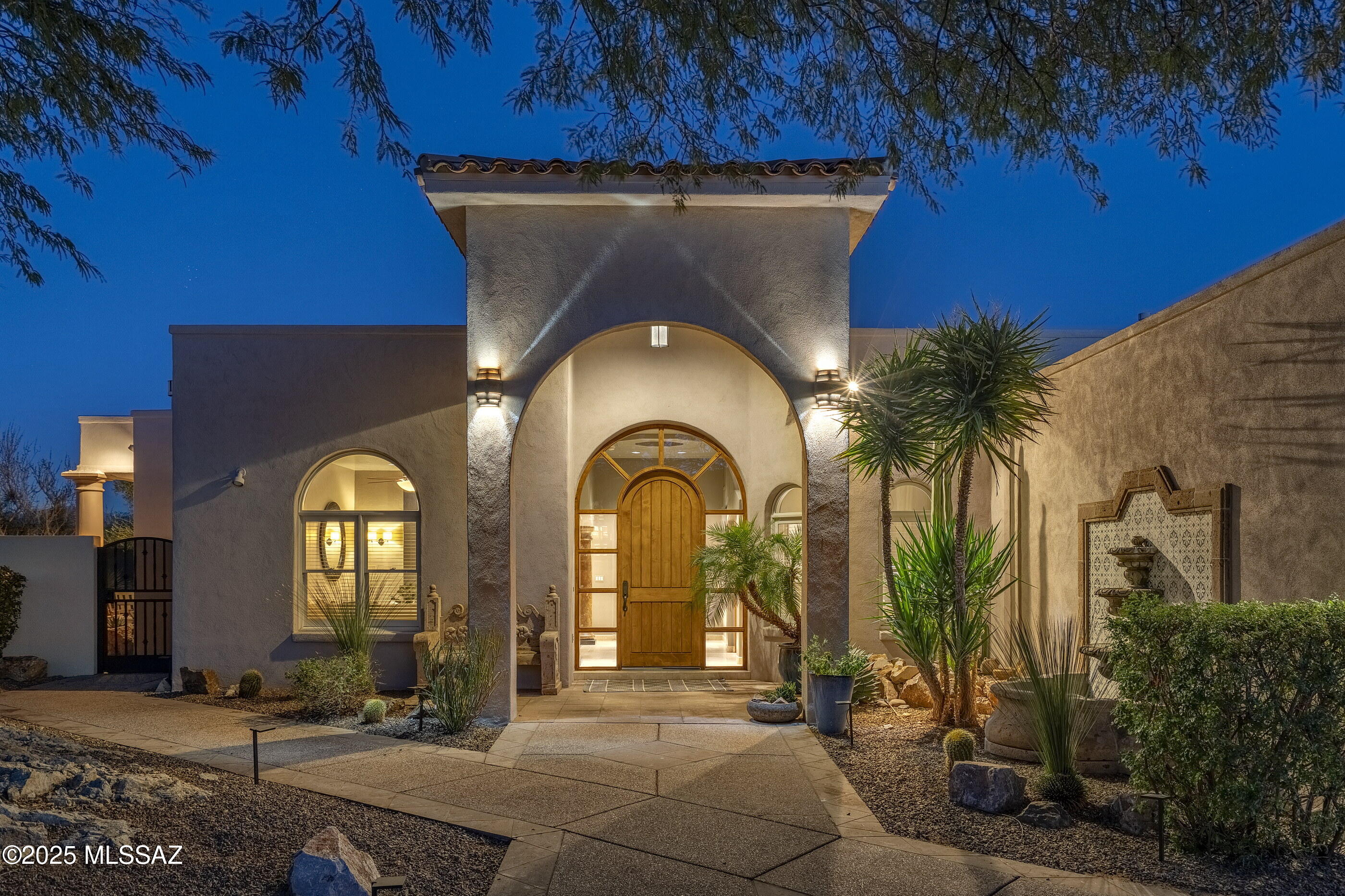 Set on a private cul-de-sac with wide open Catalina Mountain views and direct access to untouched desert, this custom southwestern contemporary property brings a level of sophistication and ease that defines the Oro Valley lifestyle. Built with concrete block and steel and finished with exceptional craftsmanship, the residence offers a sense of quiet luxury, absolute privacy, and an effortless connection to the surrounding landscape that will resonate with the most discerning buyers. The east facing backyard frames dramatic mountain scenery and opens to the Vistoso Trails Nature Preserve, with miles of walking and biking paths and immediate access to world class golf. A wraparound patio finished with Cantera tile sets the tone for outdoor living. The space includes a Napoleon BBQ with granite counter, bar with sink, outdoor fireplace with television, imported wrought iron fencing, and a magnificent Mediterranean inspired Pebble Tec heated pool and spa with dual water features and a self cleaning system. Evening light, mountain silhouettes, and the soft sound of water creates a tranquil retreat.

Inside, the home reveals thoughtful design and refined detail. Travertine floors, four fireplaces, and custom alder woodwork add warmth throughout, with rolling shutters, zoned HVAC, and solid masonry construction ensure optimal comfort. The great room captures panoramic mountain views and features a beehive fireplace, recessed lighting, custom designer paint, and an elegant dining area accented by pendant lighting.

The gourmet kitchen is a centerpiece of the home. Cherry cabinetry, granite counters, and a stylish tile backsplash pair with premium stainless appliances including a Sub Zero refrigerator, Asko dishwasher, Dacor stainless suite with oven, microwave, warming drawer, and a sleek cooktop with retractable vent. A generous island, breakfast bar with pendant lighting, and a dedicated wine bar with a fifty-four bottle cooler complete the space.

The owner's suite provides a private sanctuary with a fireplace, custom closets with cherry finish, and Jeld Wen solid alder doors with bronze hardware. The spa inspired bath includes a walk-in shower with custom inlay windows that look toward the pool and natural surroundings, a jetted tub with views, dual vanities, and premium Kohler and Grohe fixtures.

Each guest suite offers its own private bath, creating an ideal layout for hosting family and friends. A separate den with glass pocket doors offers a quiet retreat or work space. Additional features include solid copper plumbing, surround sound inside and out, a grand arched entry door with custom cast bronze handle, and a spacious three car garage.

This property brings together luxury, privacy, craftsmanship, and natural beauty. A rare offering in Vistoso Highlands and an exceptional expression of the Oro Valley lifestyle.