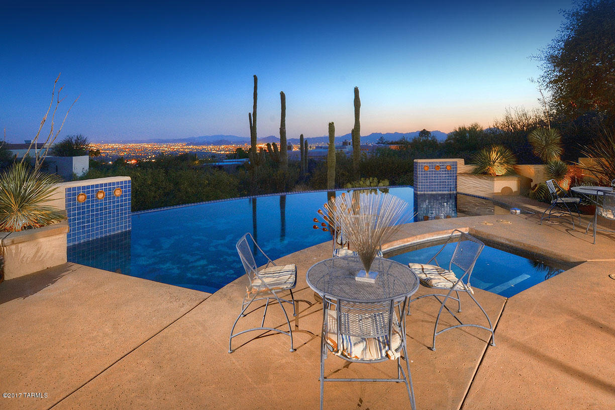 Immaculate contemporary custom home sitting high above Tucson with outstanding city lights and mountain views. This 4 bedroom/3.5 bath features high ceilings, wall space for art work, spacious living room with picture windows, formal dining room and kitchen open to the family room with wood beams ceiling. Large master suite with huge walk-in closet. Outdoors relax under the covered patio that overlooks the beautiful cactus garden, pool and spa.