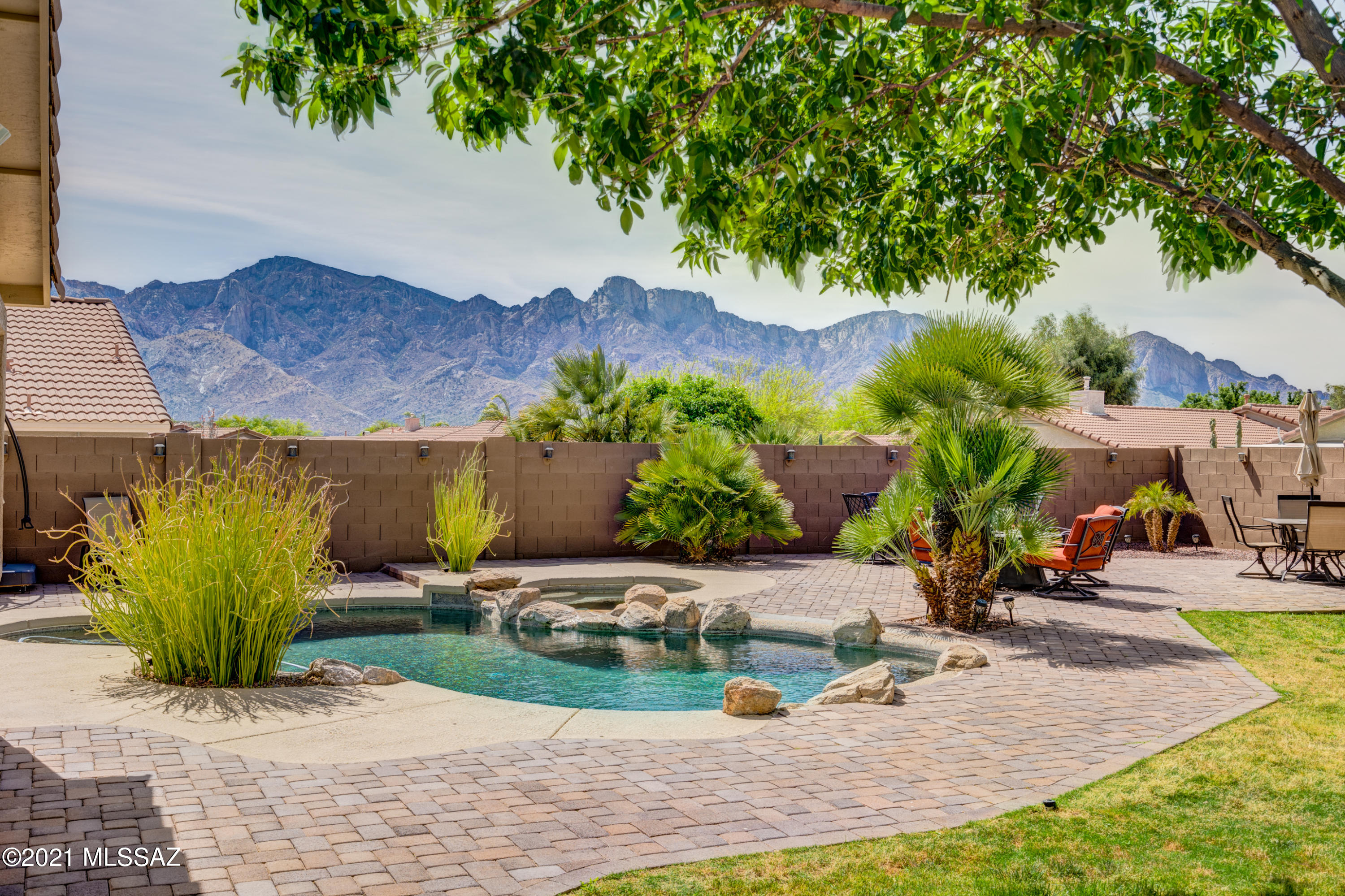 Looking for PRIVACY and VIEWS? Stunning home is an entertainers dream with a huge backyard oasis! Enjoy gorgeous Catalina Mountain views from your sparkling heated pebble-tec pool & spa, outdoor kitchen, misters, expansive paver decks, plus mature trees shading the grassy lawn! Wall extended for extra privacy with solar lights twinkling in the evening, a true retreat. Greatroom floorplan feels spacious with vaulted ceilings and wood look ceramic tile. Full of upgrades, surround sound prewired to ceiling speakers plus covered patio. Custom tiled walk-in shower with soaking tub in the master suite. Open kitchen with premium soft-close cabinetry, gas range, large island with storage, pantry closet, stainless appliances & quartz countertops. Leased Solar saves on electric bills. Must See!