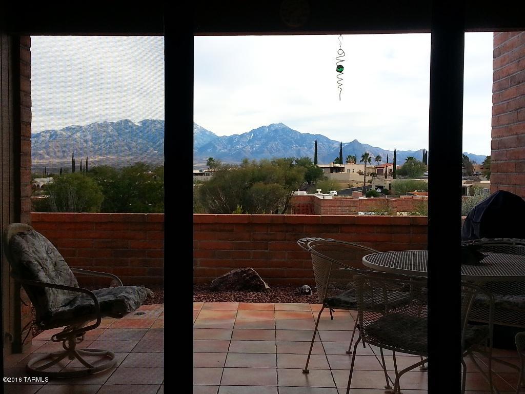 Light and bright end unit abuts common area and boasts excellent panoramic views of the Santa Rita Mountain Range. Nicely decorated interior with plantation shutters on window over dining area overlooking common area with mature trees and mountains. All newer, Kenmore stainless steel appliances. Super efficient Pullman kitchen. Easy care ceramic tile floors in living and traffic areas. Updated light fixtures, heating & cooling and water heater approx. 5 years old. Everything is done right making this easy to move into without worrying about painting, updating or furniture. Stylish furniture is all included! Enlarged rear patio and covered porch has ceramic tile flooring. Termite warranty transfers with property. Choice location!