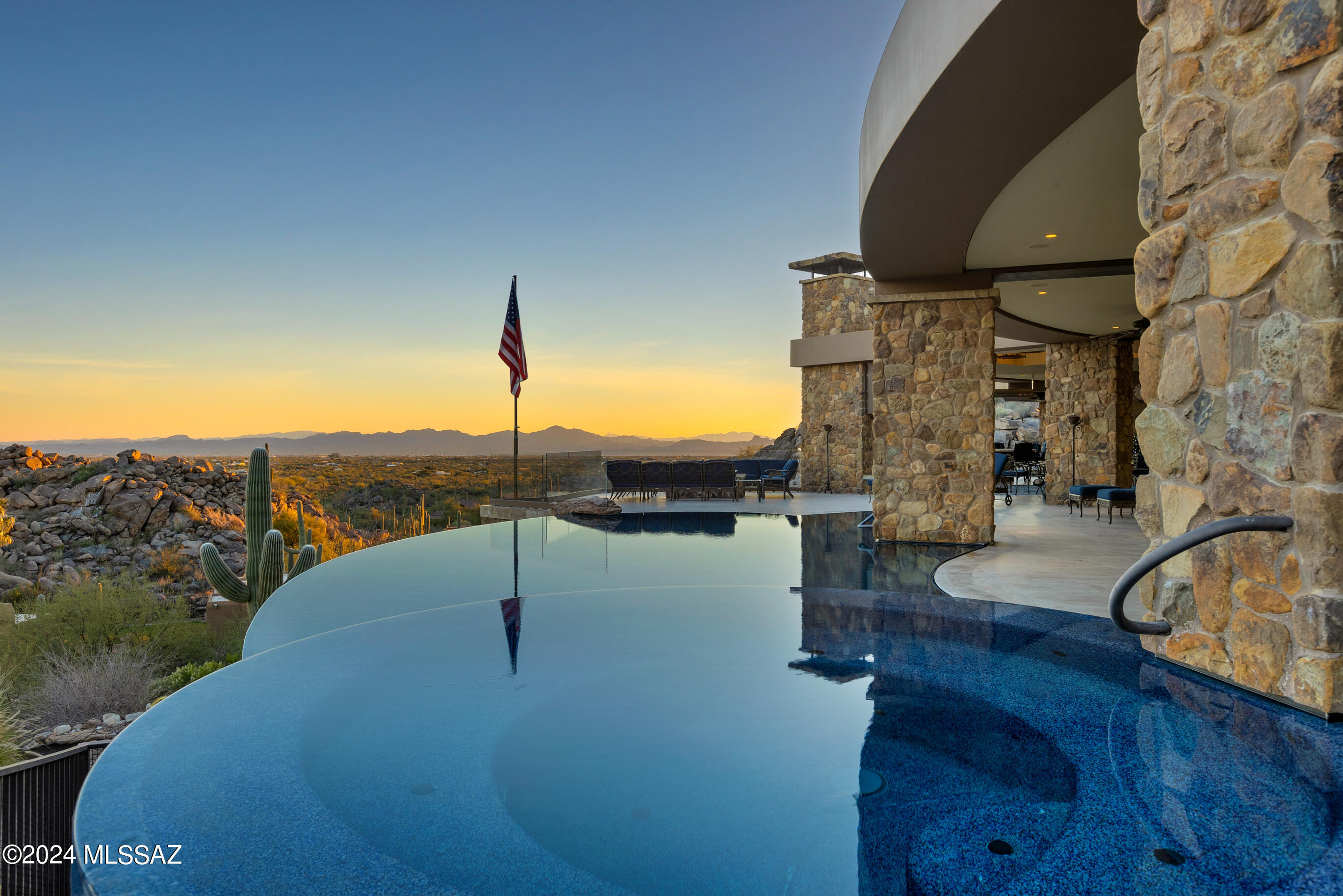 The jewel of prestigious Stone Canyon, this magnificent ridgetop estate spans a sprawling 2.18-acre lot with more than 9,500 sqft of living space, boasts breathtaking panoramic views sweeping from downtown Tucson across the impressive Santa Catalina Mountains to Mt Lemmon, and offers an exquisite living experience second to none. Lavishly appointed with rich hardwoods, intricate stonework, and crystal chandeliers, the home provides dramatic entertaining spaces that flow out to the 2400 sqft covered patio perched over the desert below.
The 8111 sqft four-bedroom, five-bathroom main house and 1442 sqft two-bedroom, two-bathroom guest house were tastefully designed by renowned architect Ron Robinette.  Meticulously crafted with uncompromising quality, this luxurious masterpiece is ready to welcome you home.
The main house boasts an impressive rotunda foyer, flowing indoor-outdoor entertainment space, and a dream chef's kitchen with adjacent catering kitchen. 
The living room is anchored on one end by a stately herringbone-patterned limestone fireplace, and is framed by a crescent wall of windows to take in the breathtaking views - perfect for hosting elegant gatherings or enjoying peaceful evenings with family. The expansive room curves around, offering space for a grand piano and additional sitting area, and flows into the elegant formal dining room featuring coffered ceilings and crystal chandeliers that lower smoothly for cleaning.
Filled with top of the line appliances from Gaggenau, Miele, Sub-Zero, and Thermador the kitchen is a canvas to create culinary masterpieces.  With an array of stacked cabinets below clerestory windows and two impressive islands below a coffered ceiling, the kitchen is the cozy heart of the home.  It overlooks the family room that converts to a theater room at the touch of a button. 
 The sophisticated owner's suite is a spa-inspired oasis of peace and serenity, with walls of windows to take in the breathtaking vistas, an impressive limestone corner fireplace, private patio access, and a luxurious ensuite featuring a steam shower, drying room, soaking tub, Numi water closet and opulent closet/dressing room.
The artfully imagined patio is designed to maximize the views beyond with a stunning glass patio railing system that gives the feeling of being able to step into the desert. Whether entertaining large parties into the night or in cozy contemplation, you will be treated to jaw-dropping vistas that stretch for miles. The luxurious, resort-style infinity edge pool and spa seemingly merge with the surrounding landscape aside a footbridge and tranquil water feature. 
The covered outdoor kitchen has everything imaginable- built-in BBQ, cooktop, warming drawer, refrigerator, dishwasher, and sink with a bar peninsula. Adjacent, under the expansive covered portion, lies a fireplace and television, and beyond a large firepit to enjoy the evening lights. 
The enchanting library maintains the same standard of luxury as the rest of the home, with floor-to-ceiling custom walnut cabinetry, dual work stations, library shelving with dual sliding ladders, and room for a sitting area. Dark walnut moulding extends across the coffered ceiling for a truly old-world, castle-like feel.
The main house is completed with two additional ensuite bedrooms, an exercise room/4th bedroom, all with custom walk-in closets, and an oversized garage with multiple storage room and the ultimate workshop/man cave.
Your guests will luxuriate in the resort-like detached guest house with game room. Meticulously crafted with uncompromising quality, two bedrooms, two bathrooms, a full kitchen and laundry, a family room showcasing the views though a wall of windows and a private patio.
The home features its own private park complete with snake-proof fencing, a fire pit, and dog run. The area also cleverly hides an underground 1000 gallon propane tank that supplies the emergency generator.
Smart technology abounds: Lutron light and shade systems - create the perfect amount of light at the touch of a button. There is also an Accura monitored security system; a  HikVision camera system with DVR recording; Sonos audio system; and a commercial grade networking system upgraded in 2023.  
The Jewel of Stone Canyon House -- it's not just a home; it's a lifestyle statement. It's where luxury meets comfort, where every day feels like a retreat, and where you can truly live your best life. Welcome to your dream home - where every moment is an experience in unparalleled luxury and elegance.